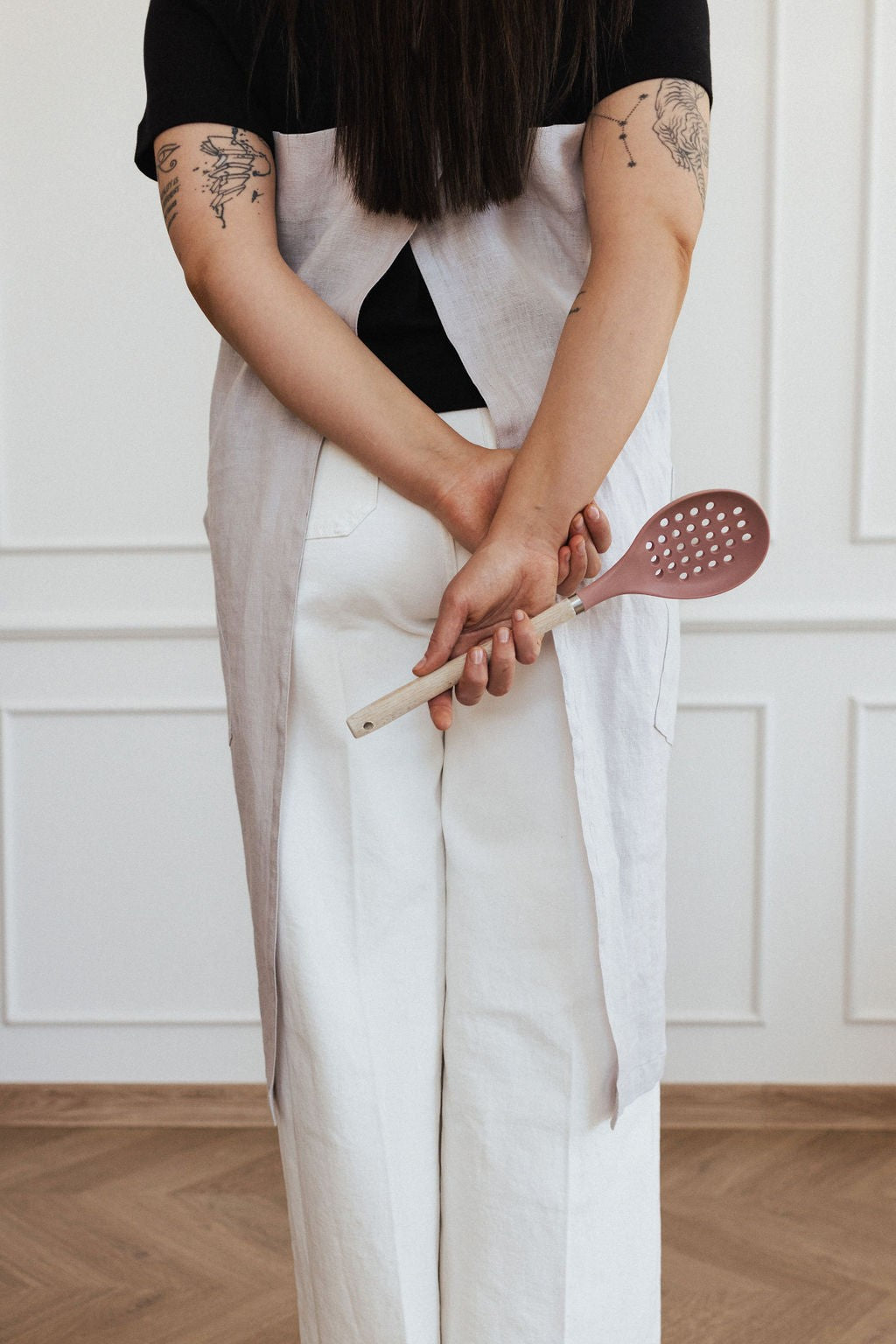 elegant linen apron with crossed back straps and two pockets, shown in warm morning light