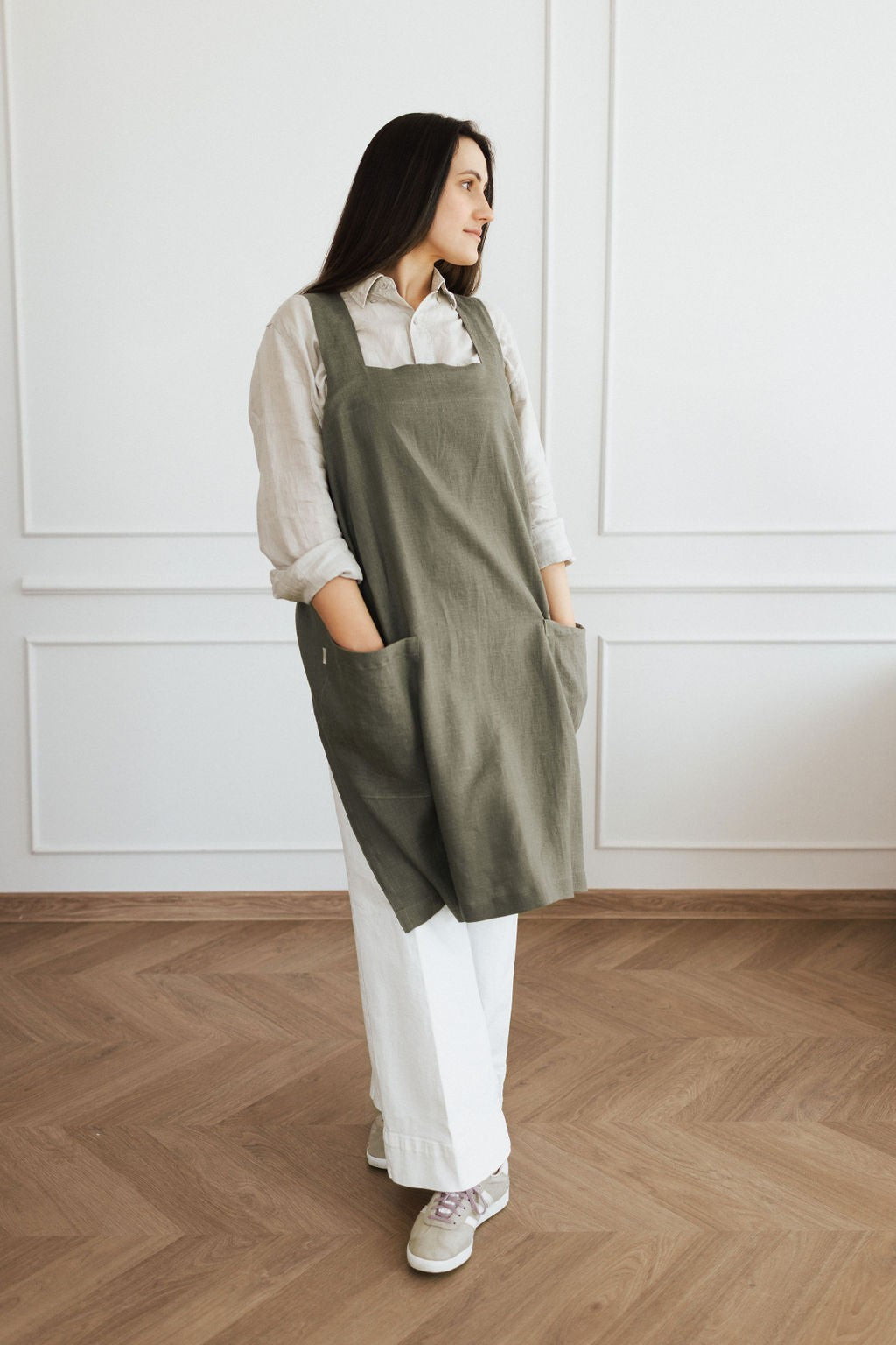elegant linen apron with crossed back straps and two pockets, shown in a warm, sunlit kitchen setting