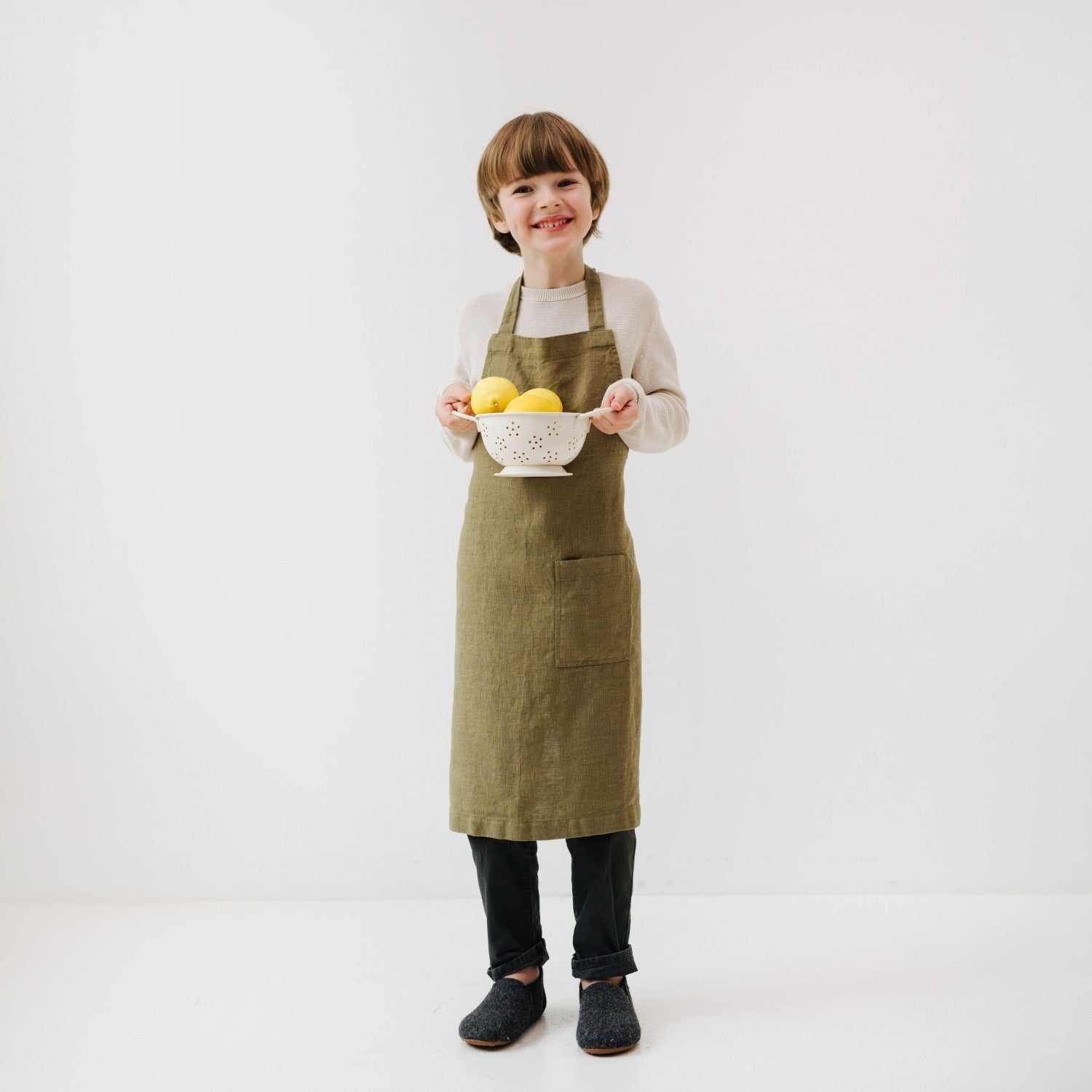 confident young chef in an olive linen apron standing in a sunlit kitchen