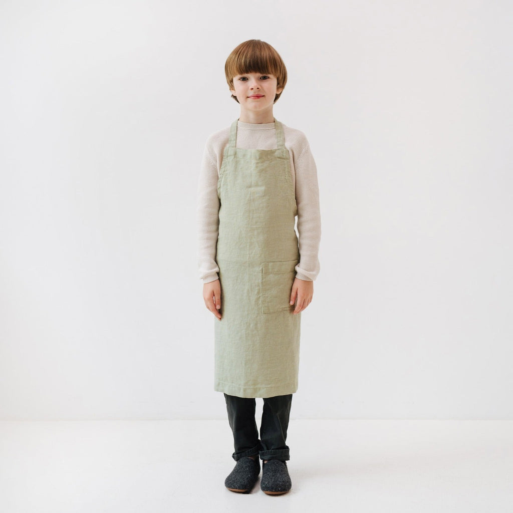 elegant sage linen kids apron with a deep front pocket, shown in soft natural light