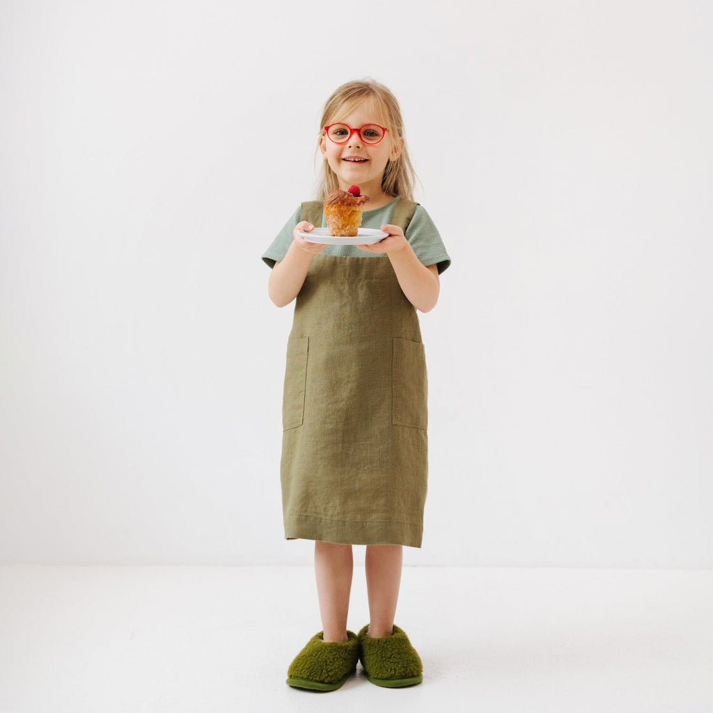 elegant olive linen kids apron with front pockets, shown in soft natural light