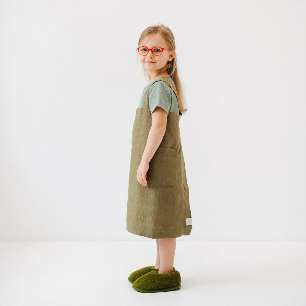 confident young chef in a stylish olive linen pinafore apron with deep pockets