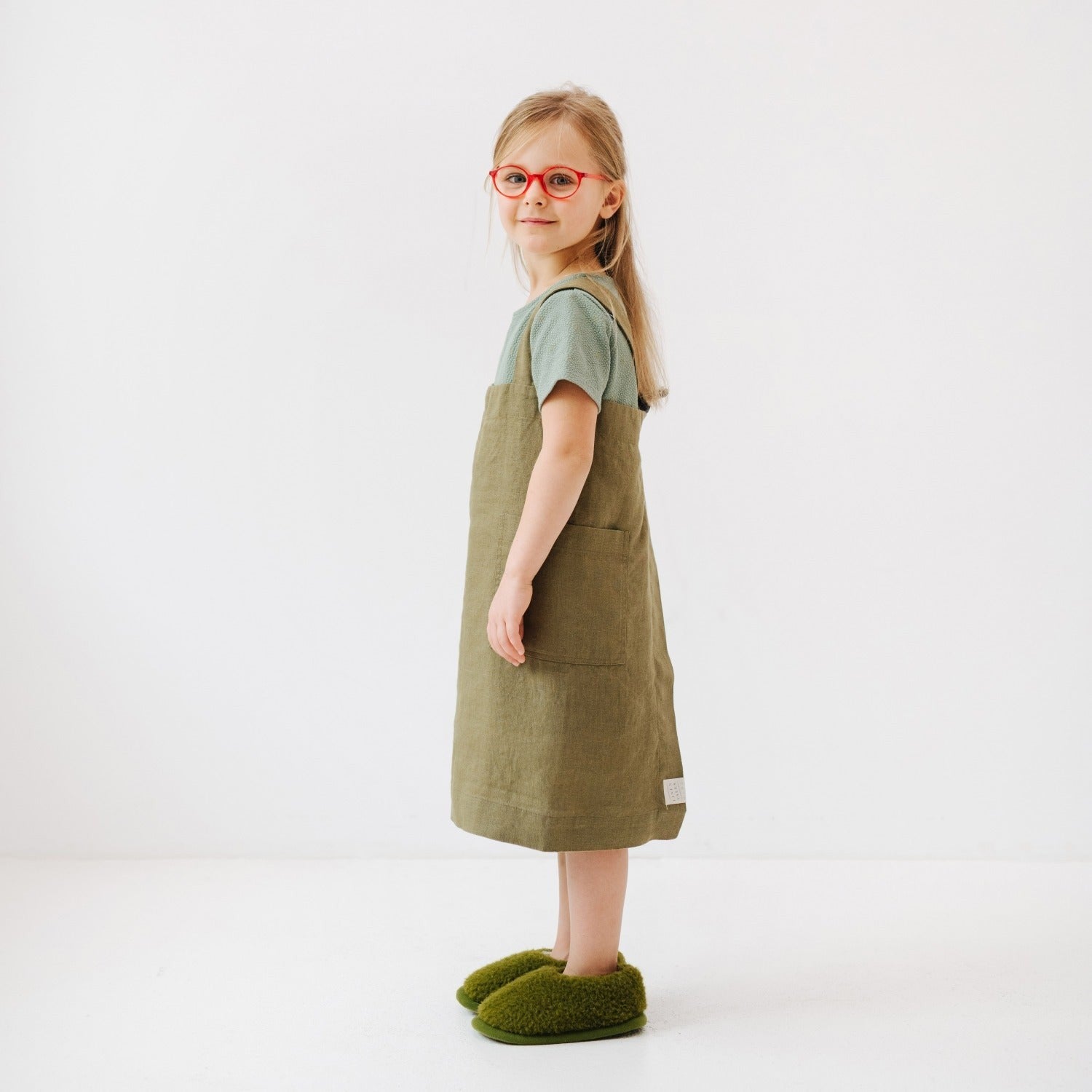 confident young chef in a stylish olive linen pinafore apron with deep pockets
