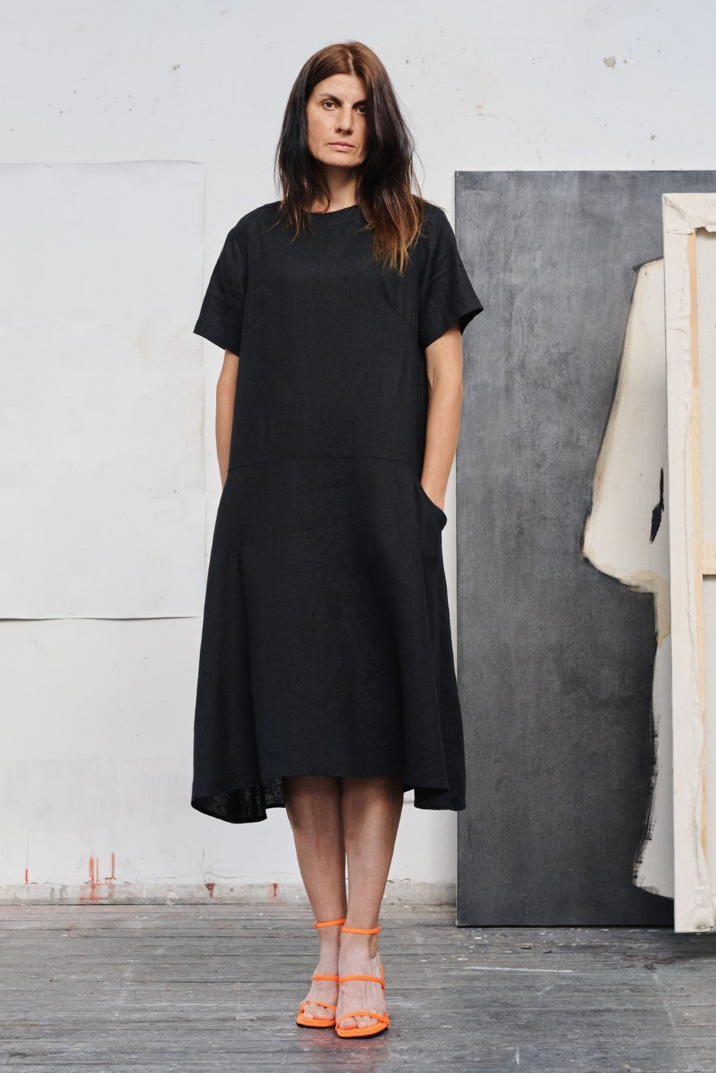 a confident woman in a black linen dress striking a bold pose against an urban backdrop