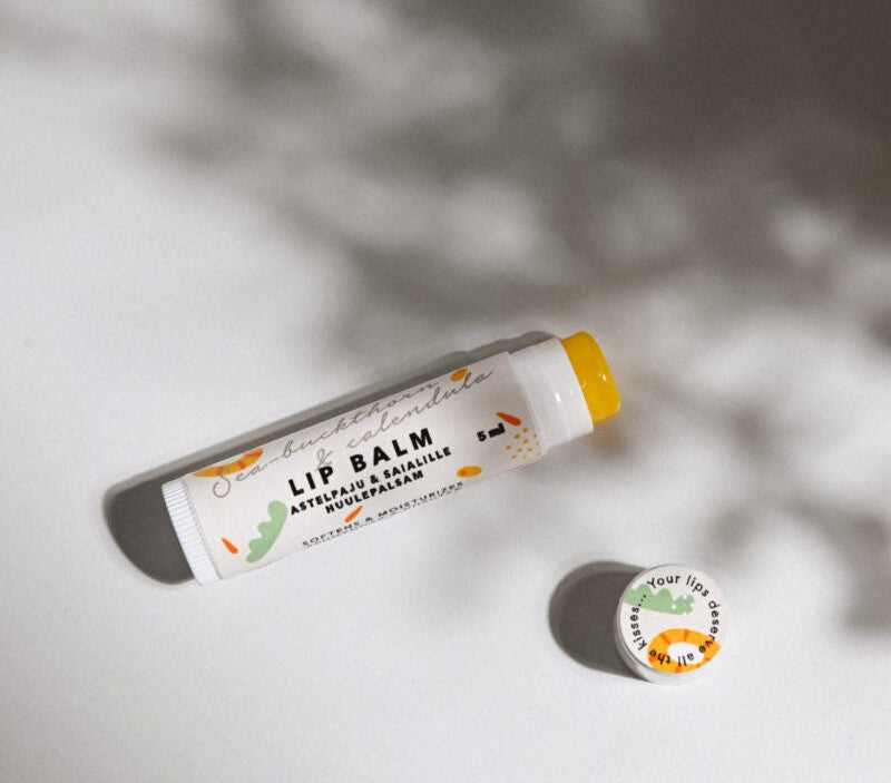a bold close-up of sea buckthorn and calendula lip balm on a contemporary leather bag