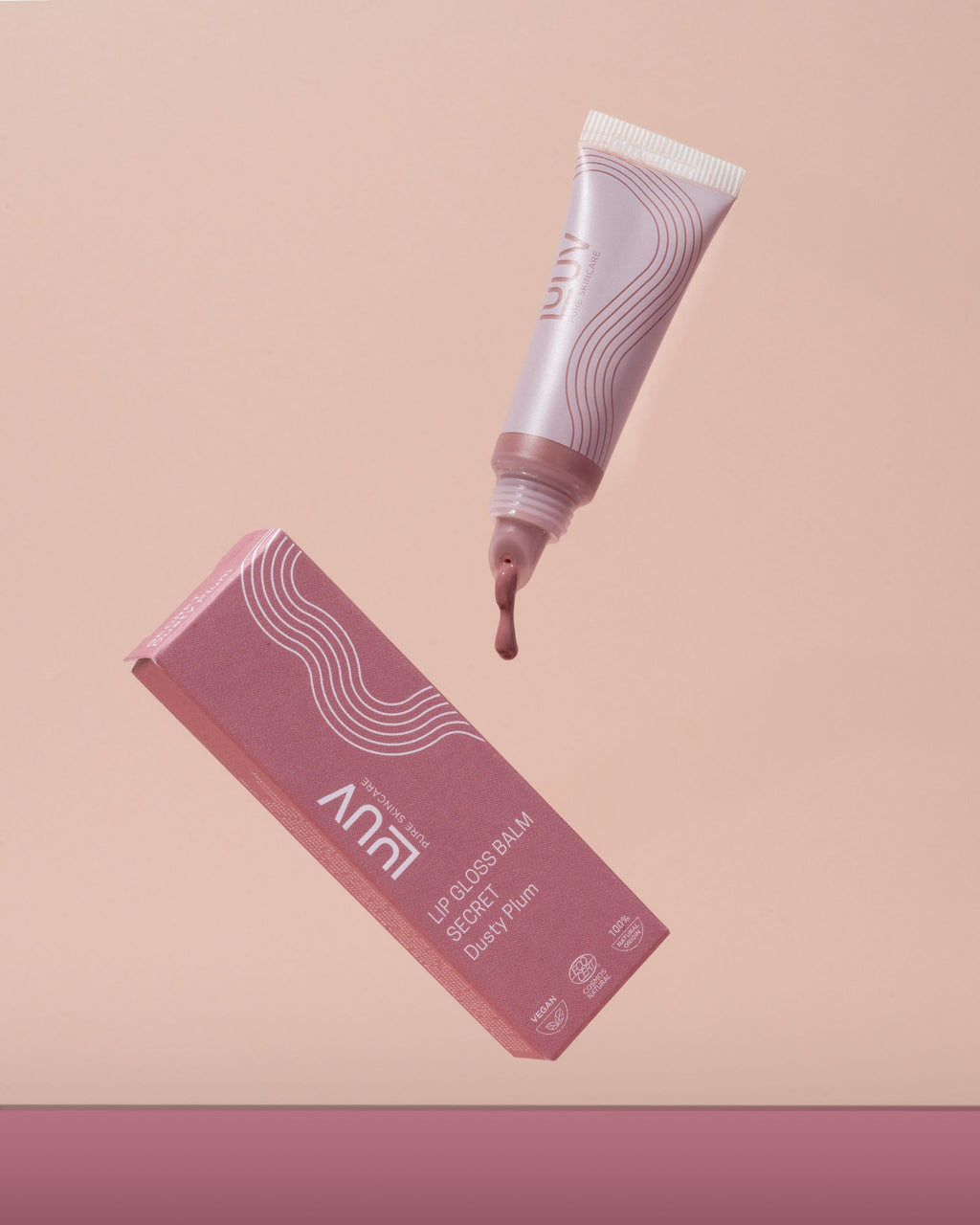 playful close-up of luuv gloss balm in hand with a vibrant, glossy sheen