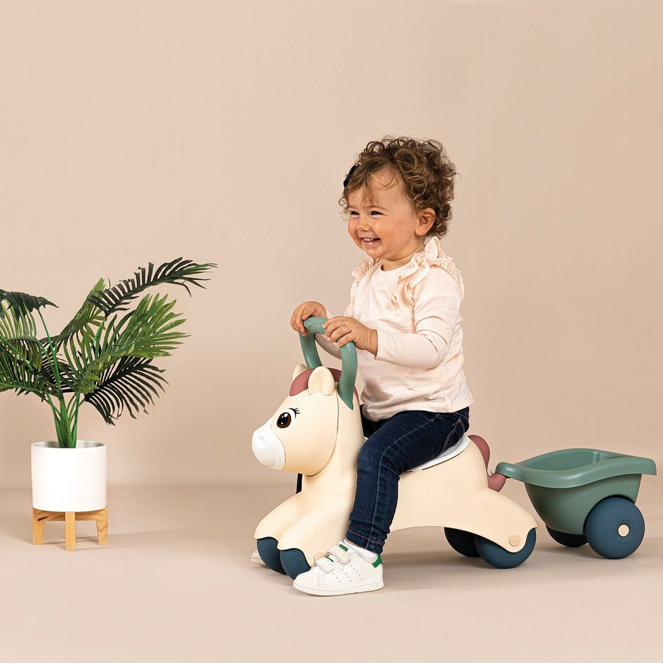 bold front view of a toddler's first ride-on pony with trailer in soft pastel colors