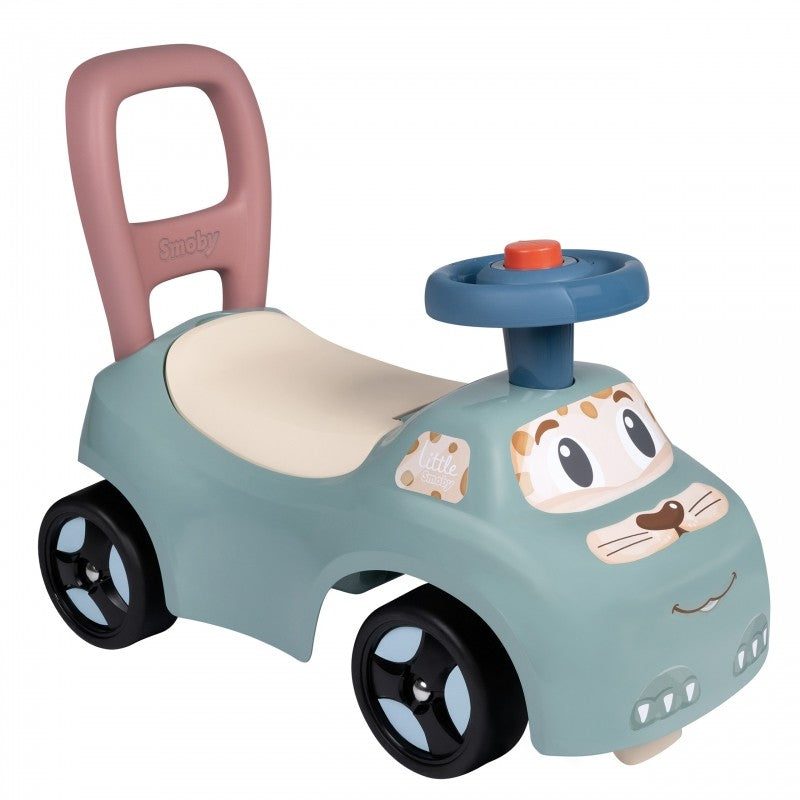 pastel blue ride-on pusher with horn, toddler pushing it on a sunny patio, learning to walk