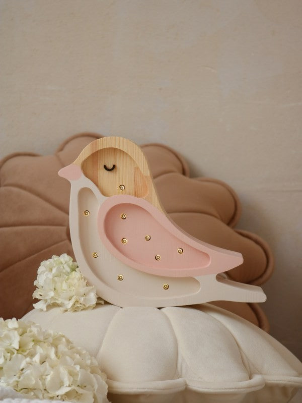 a child's hand gently touching the warm pine wood bird lamp on their nightstand