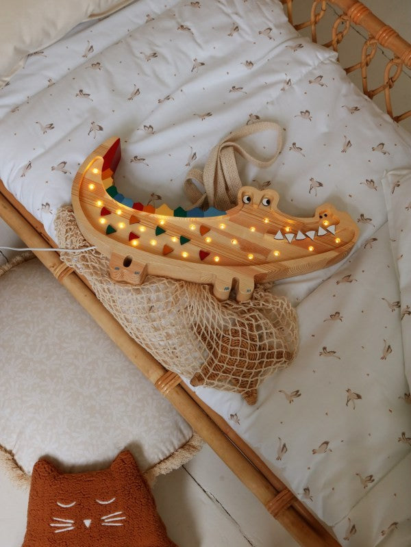 a handcrafted pine crocodile lamp casting a soft warm glow on a wooden nightstand