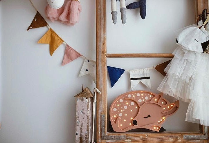 softly lit pinewood deer lamp casting a warm glow on a nursery shelf
