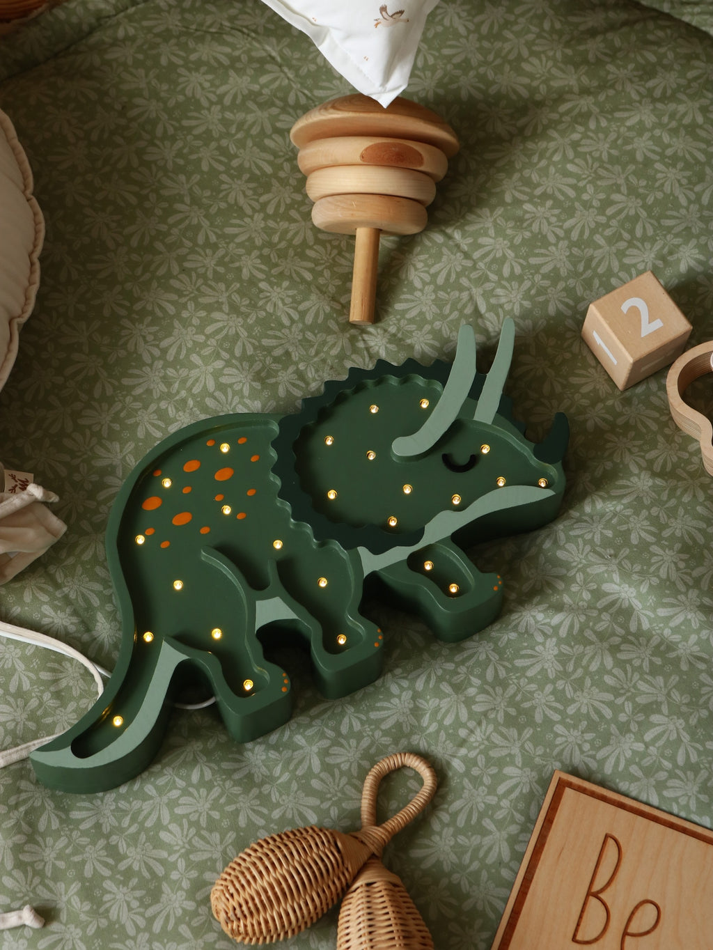 bold triceratops dino lamp casting a warm glow on a rustic wood nightstand