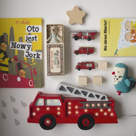 a softly glowing pine wood firetruck lamp casting a warm, comforting light in a nursery