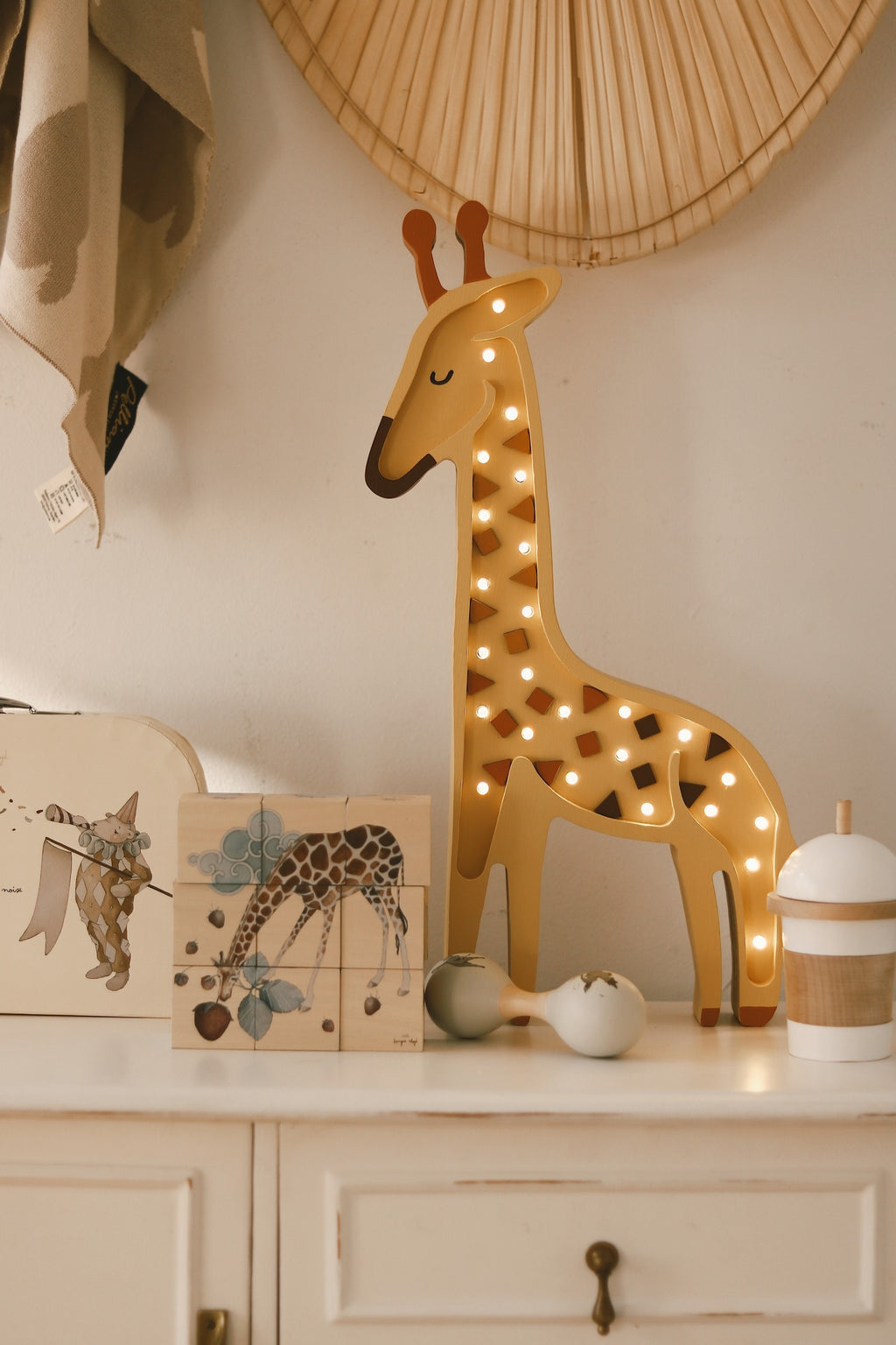 handmade giraffe lamp casting a warm glow on a cozy nursery shelf