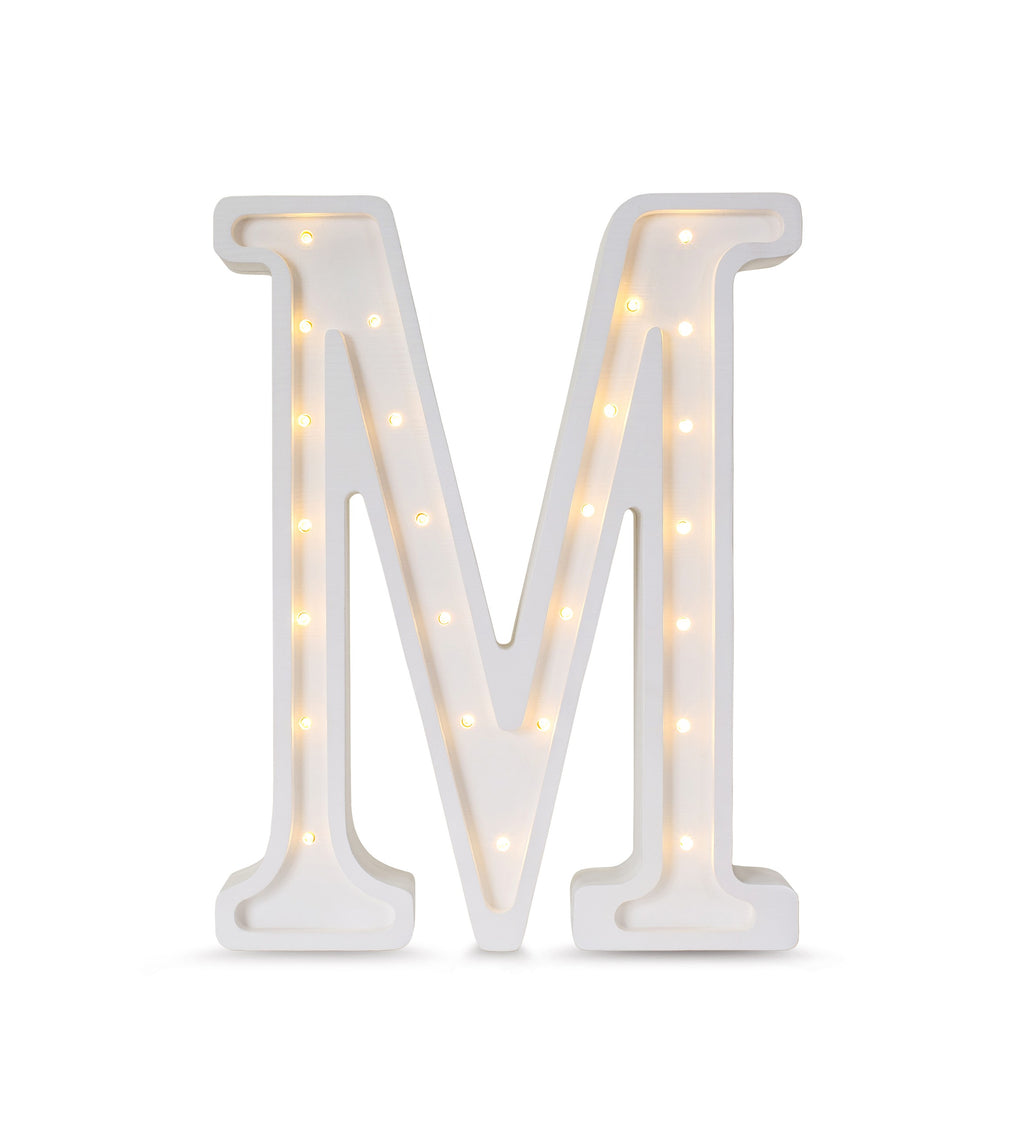 a soft-lit letter m lamp casting a warm glow on a childs bedside table