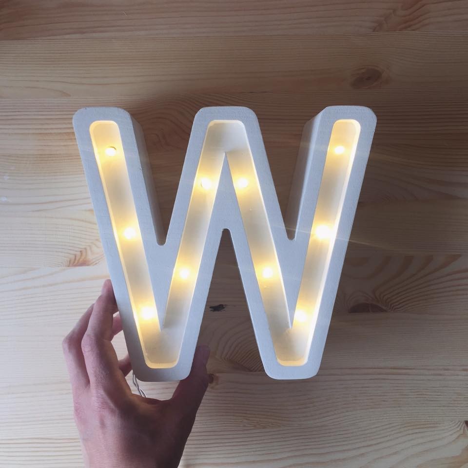 a soft-lit wooden w letter lamp glowing warmly on a nursery shelf