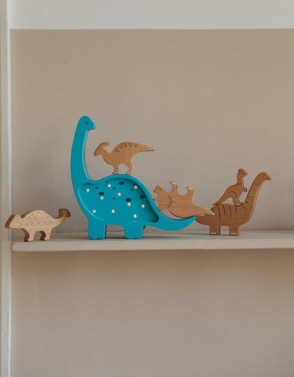 a close-up of the artisan-crafted pinewood dino lamp glowing warmly on a bedside table