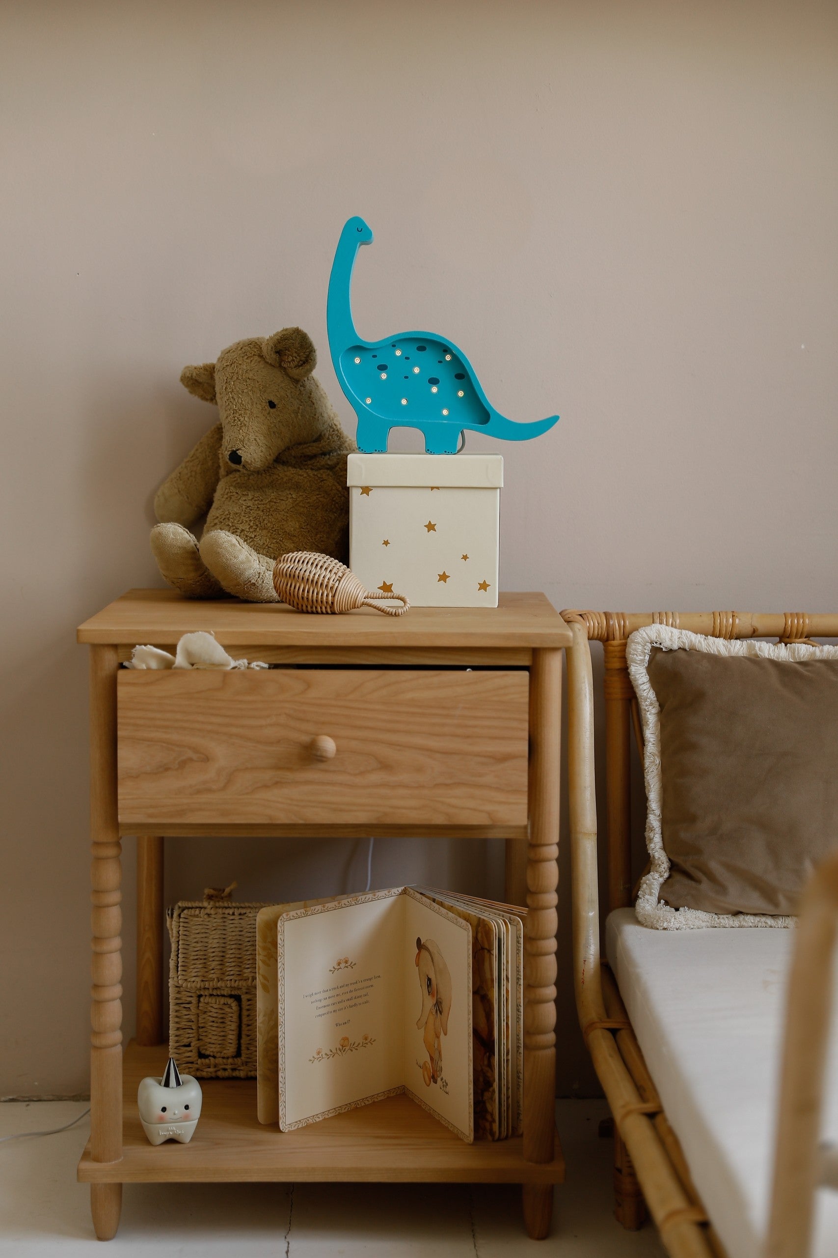 mini dino lamp casting a warm glow on a pinewood nightstand