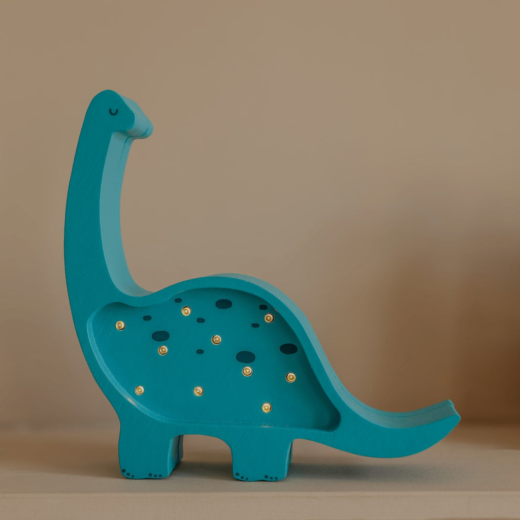a handcrafted pinewood dino lamp casting a warm glow on a child's bedside table