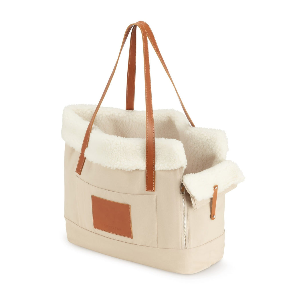 playful beige liiva dog carrier with a happy small dog peeking out of the stylish personal bag