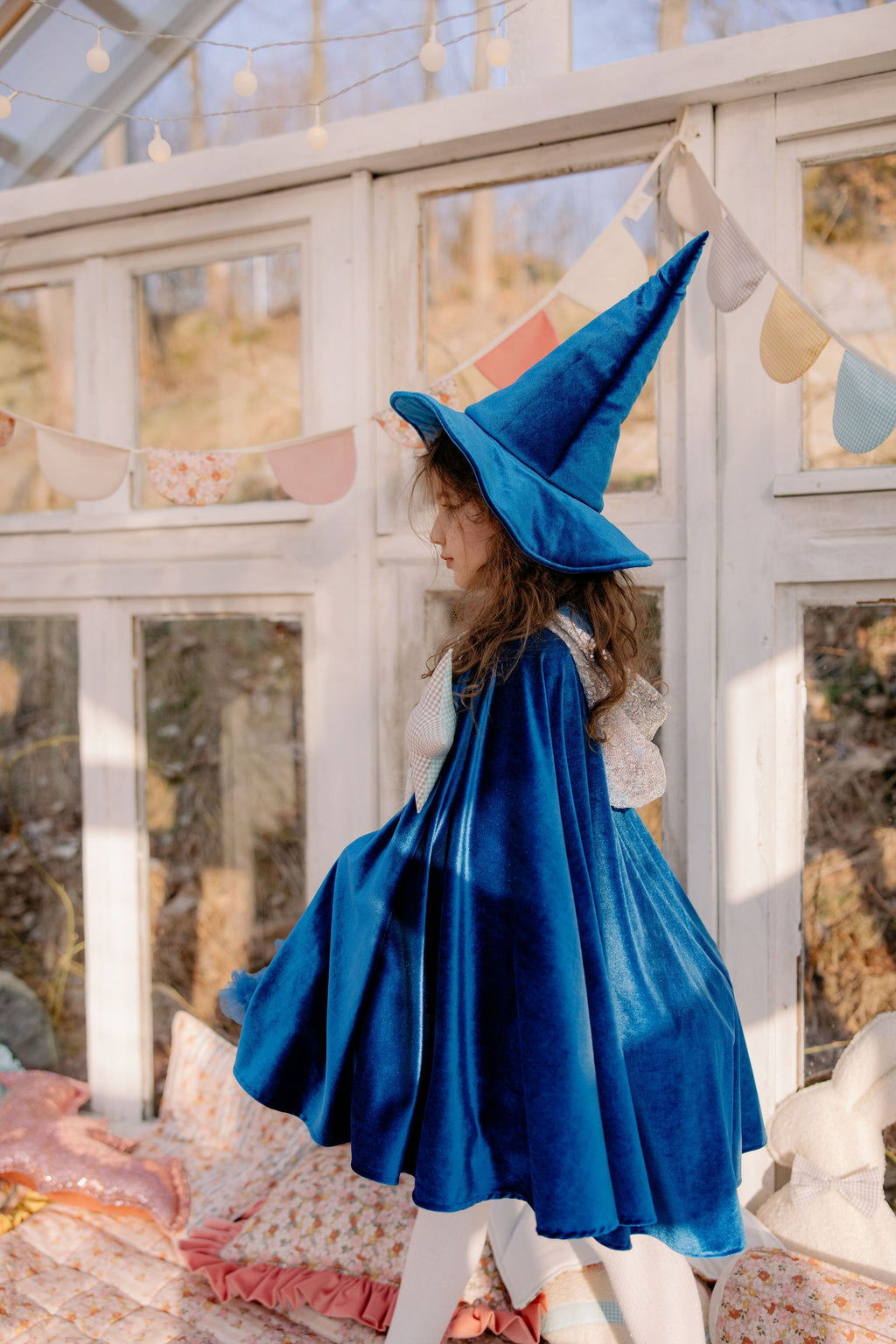 a child in a handmade blue velour snow queen cape twirling in soft morning light