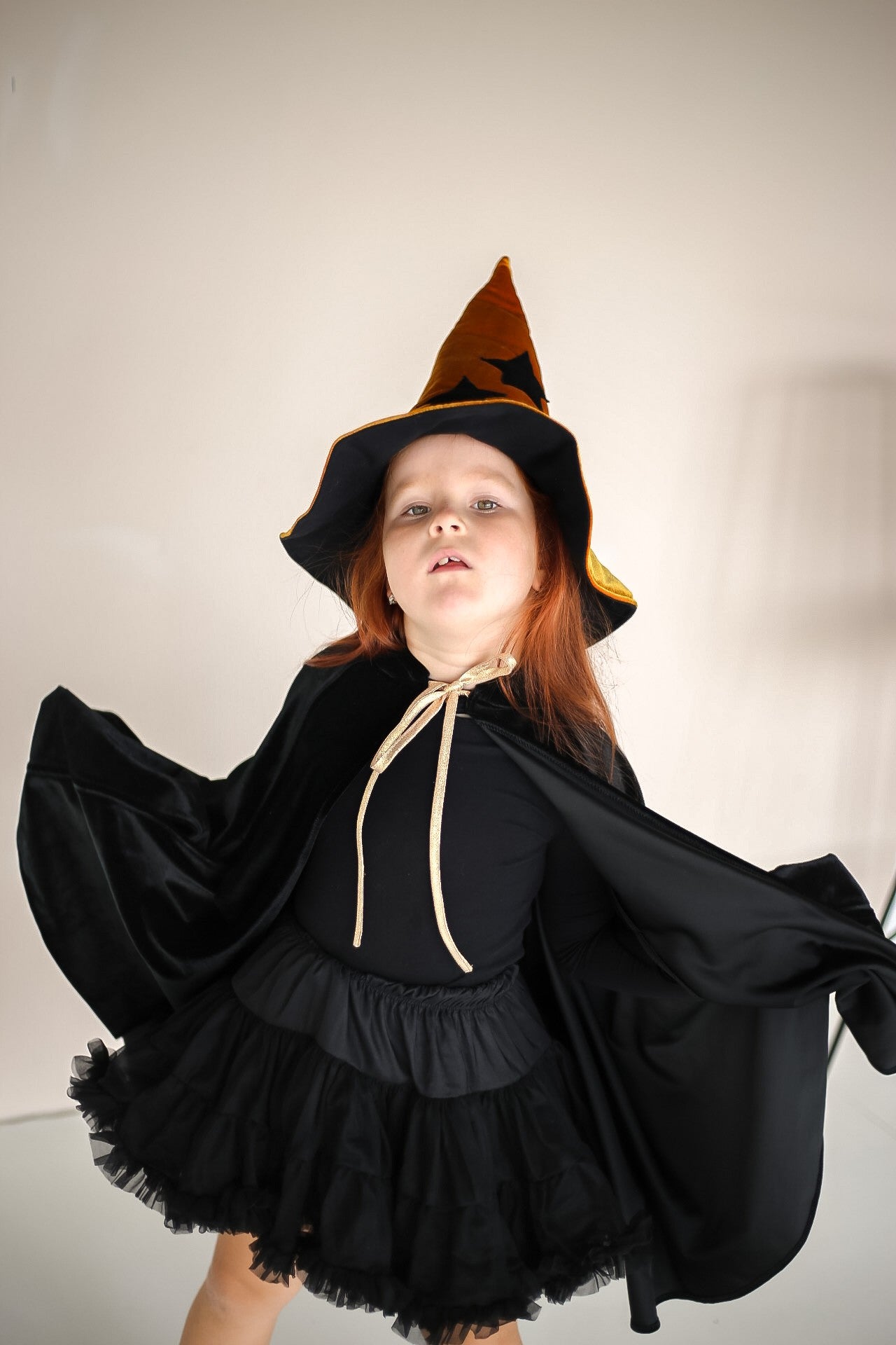 elegant black velour riding hood cape with a deep hood and snap fastening, shown in a refined side profile