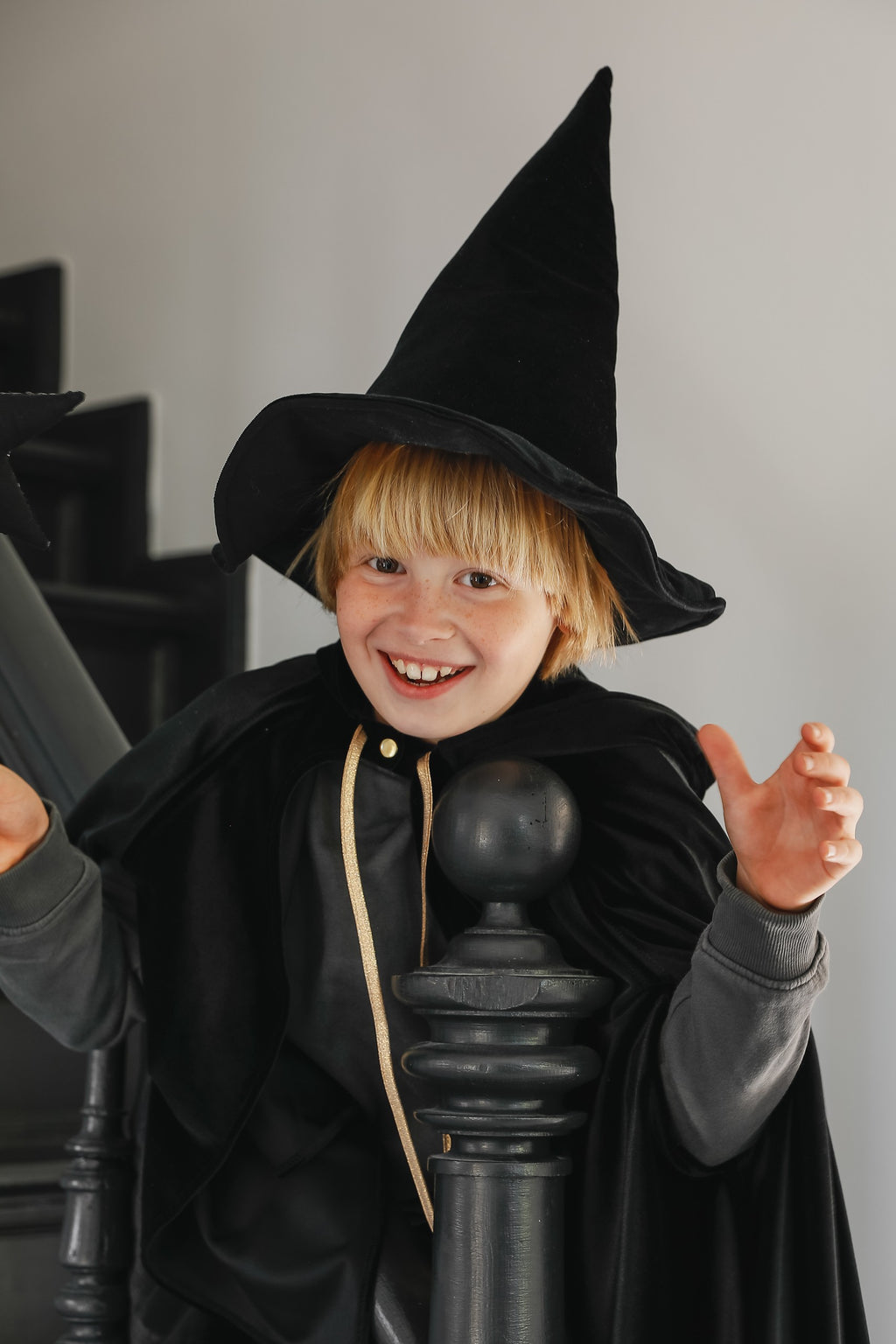 handmade black velour cape with a deep hood and snap fastening, shown from a playful angle as it swishes during a spin