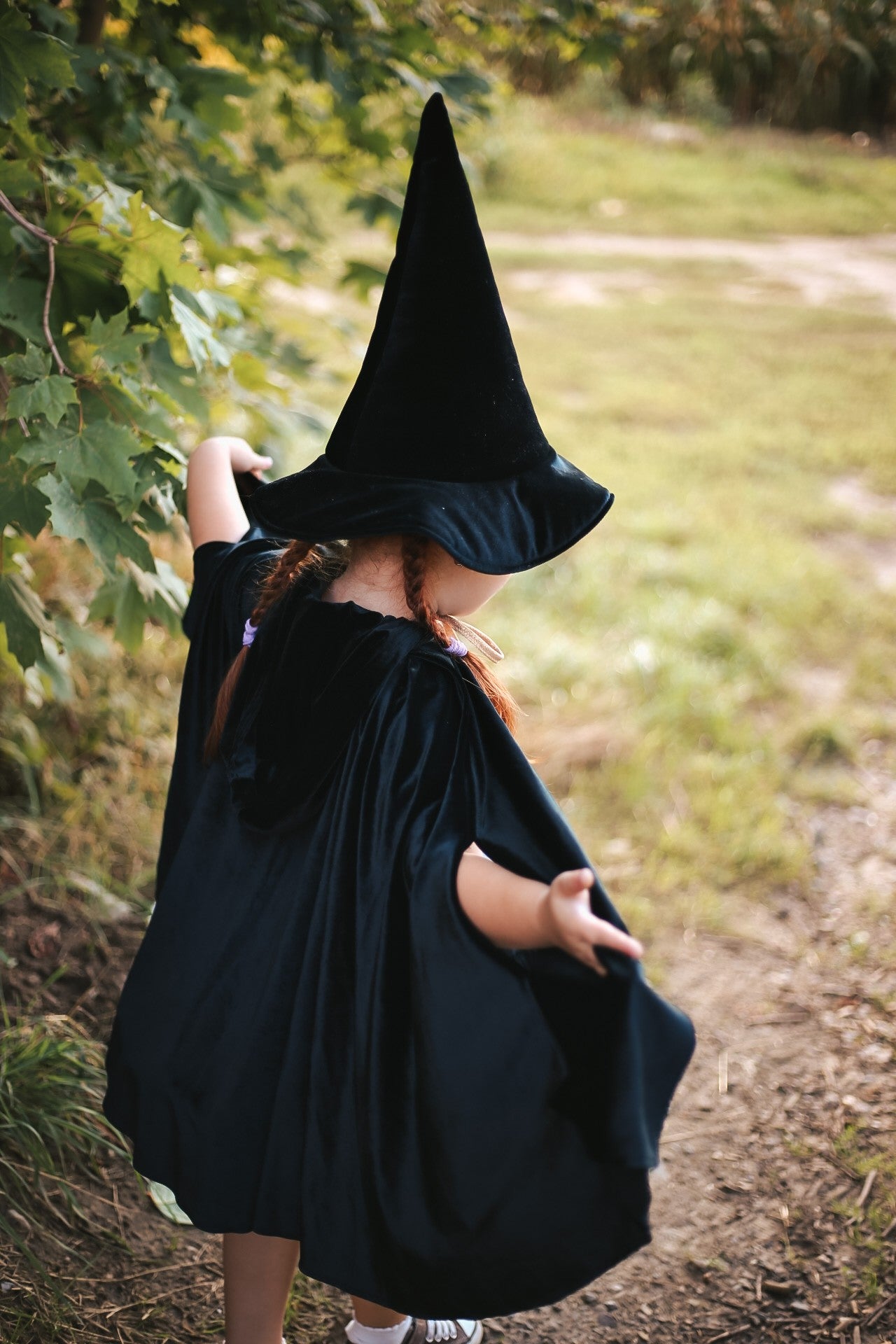 child in a dark velour hooded cape casting a magical shadow on a stone wall