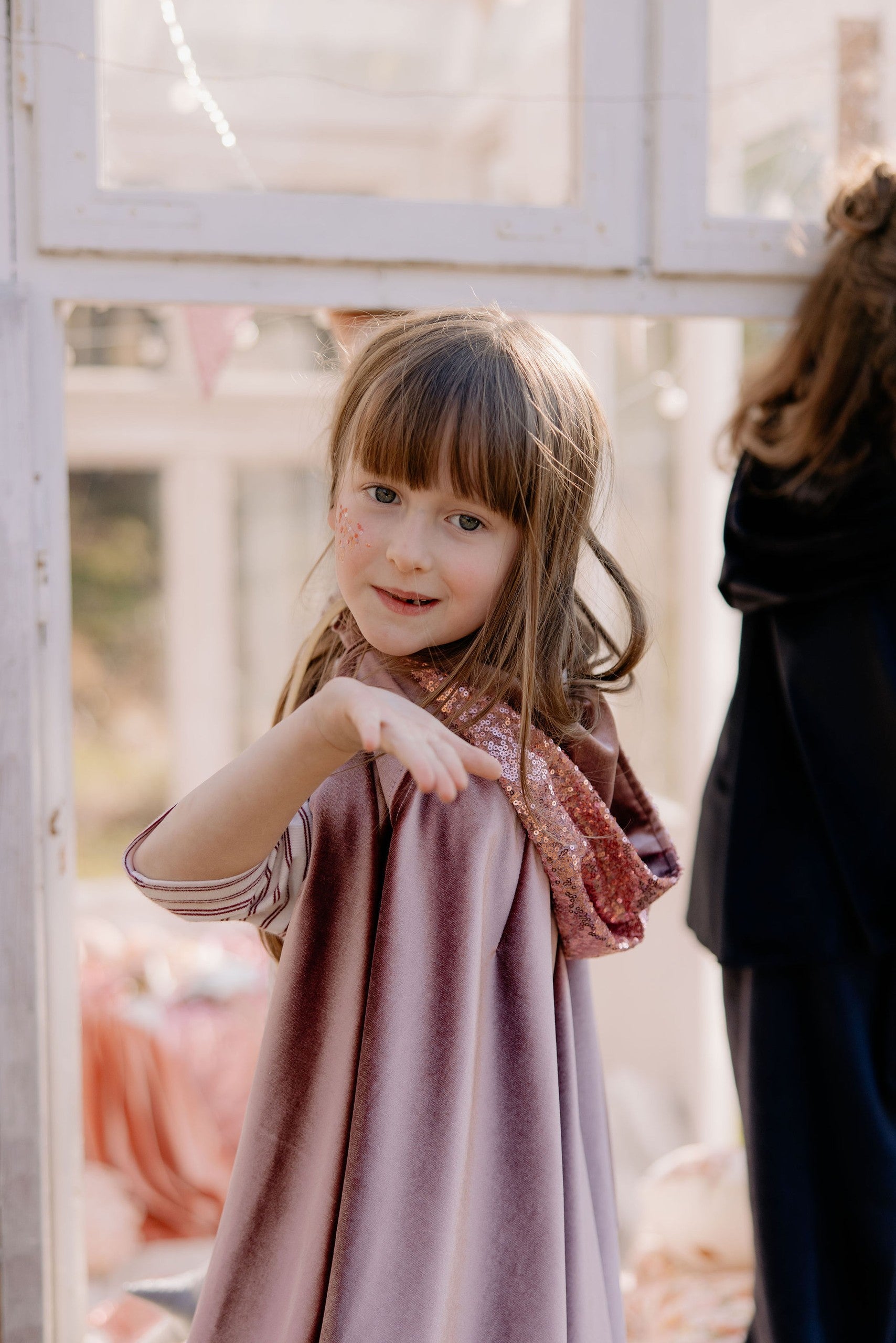 child testing the secure snap closure on a cosmic pearl velour cape
