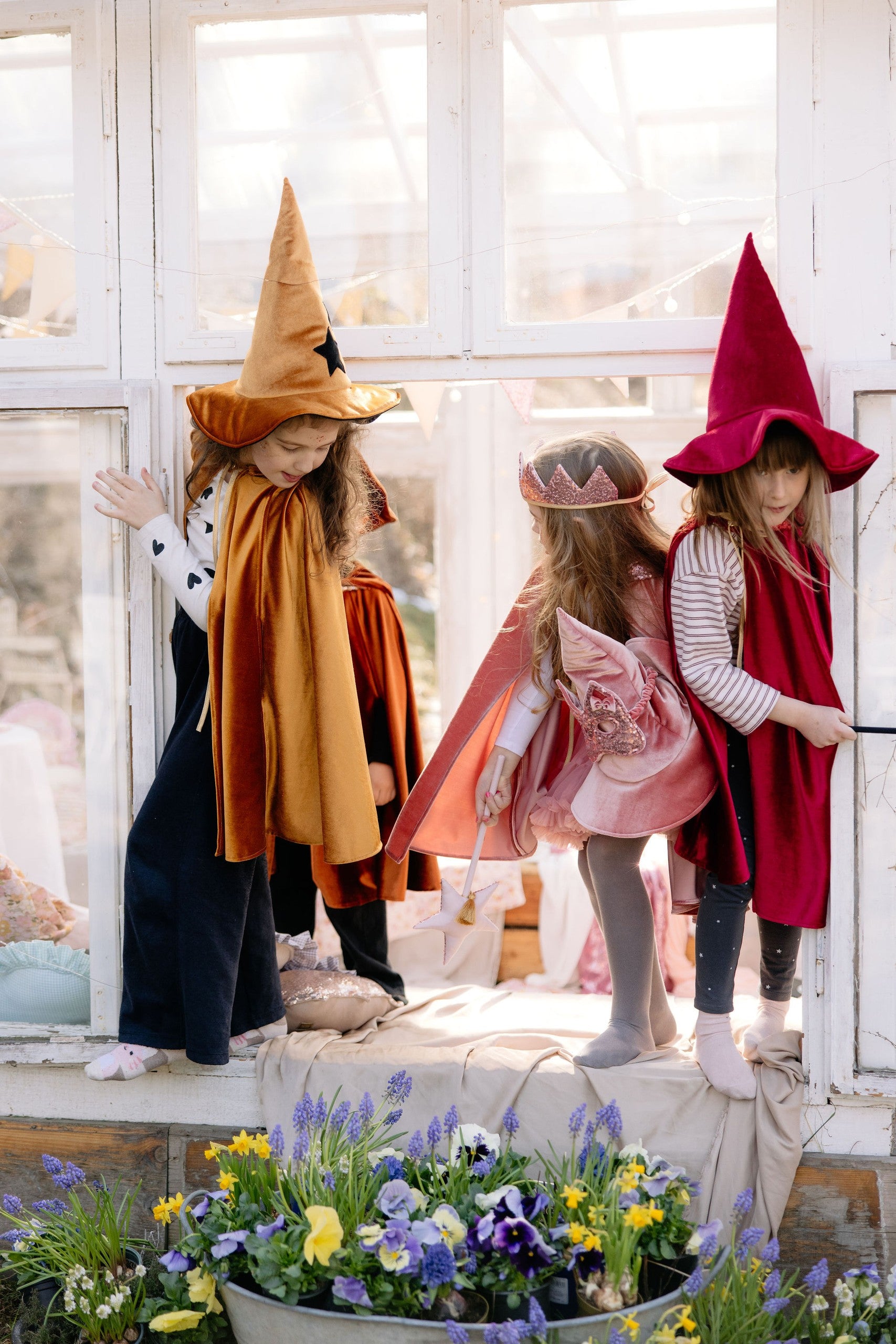 a child laughing in a golden velour hooded cape, mid-spin in a sunlit garden