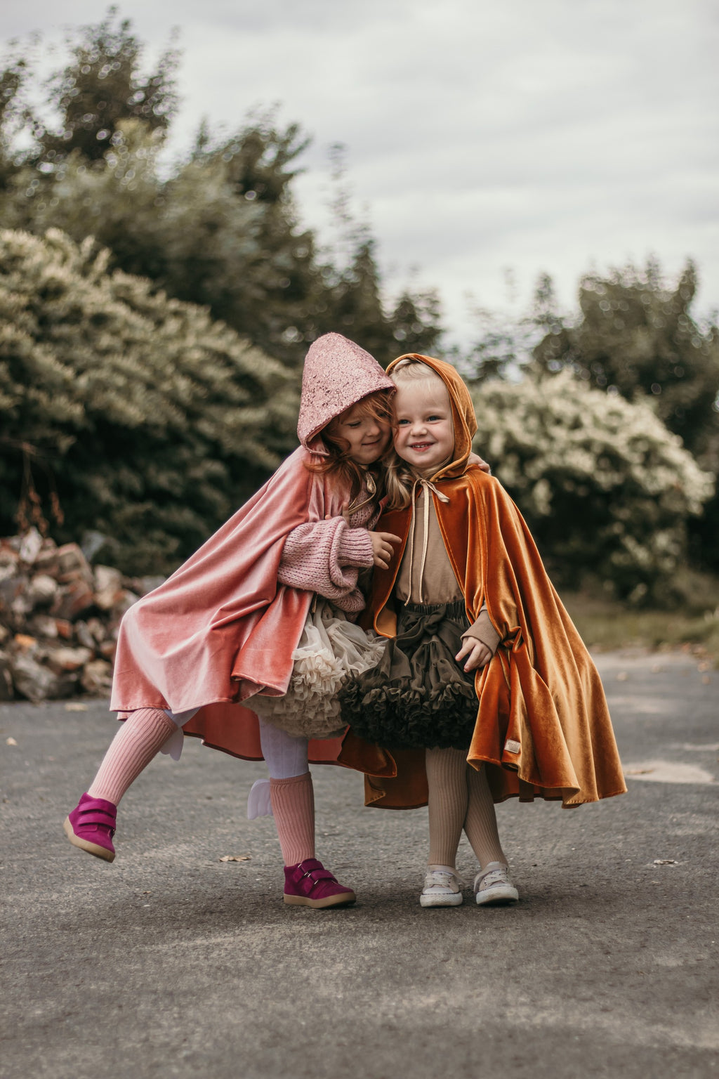 elegant pink velour riding hood cape with a deep hood, shown in soft golden light