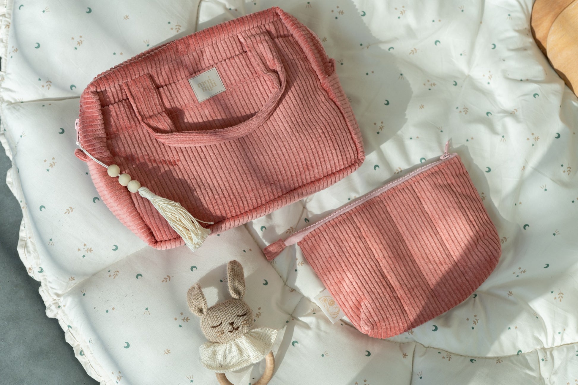 handmade coral cotton makeup bag set with two sizes open on a rustic wooden table