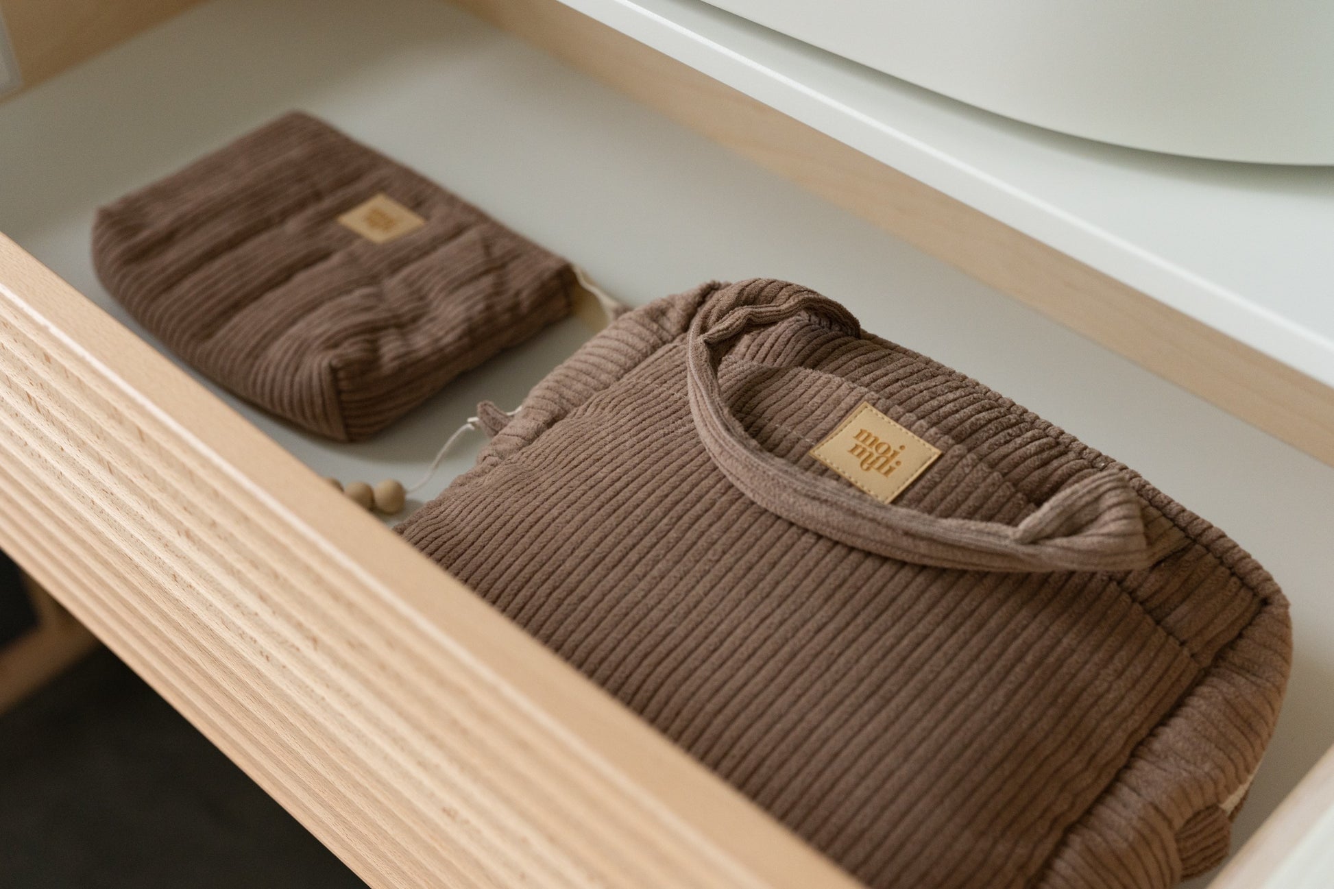 a chic latte-colored cotton makeup bag open on a table revealing its inner waterproof pocket
