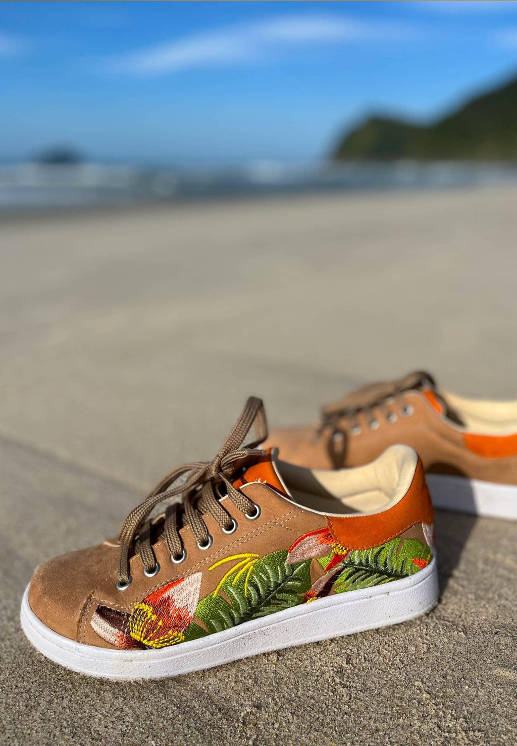 side profile of mangara floral embroidered suede sneakers on a rustic wooden deck