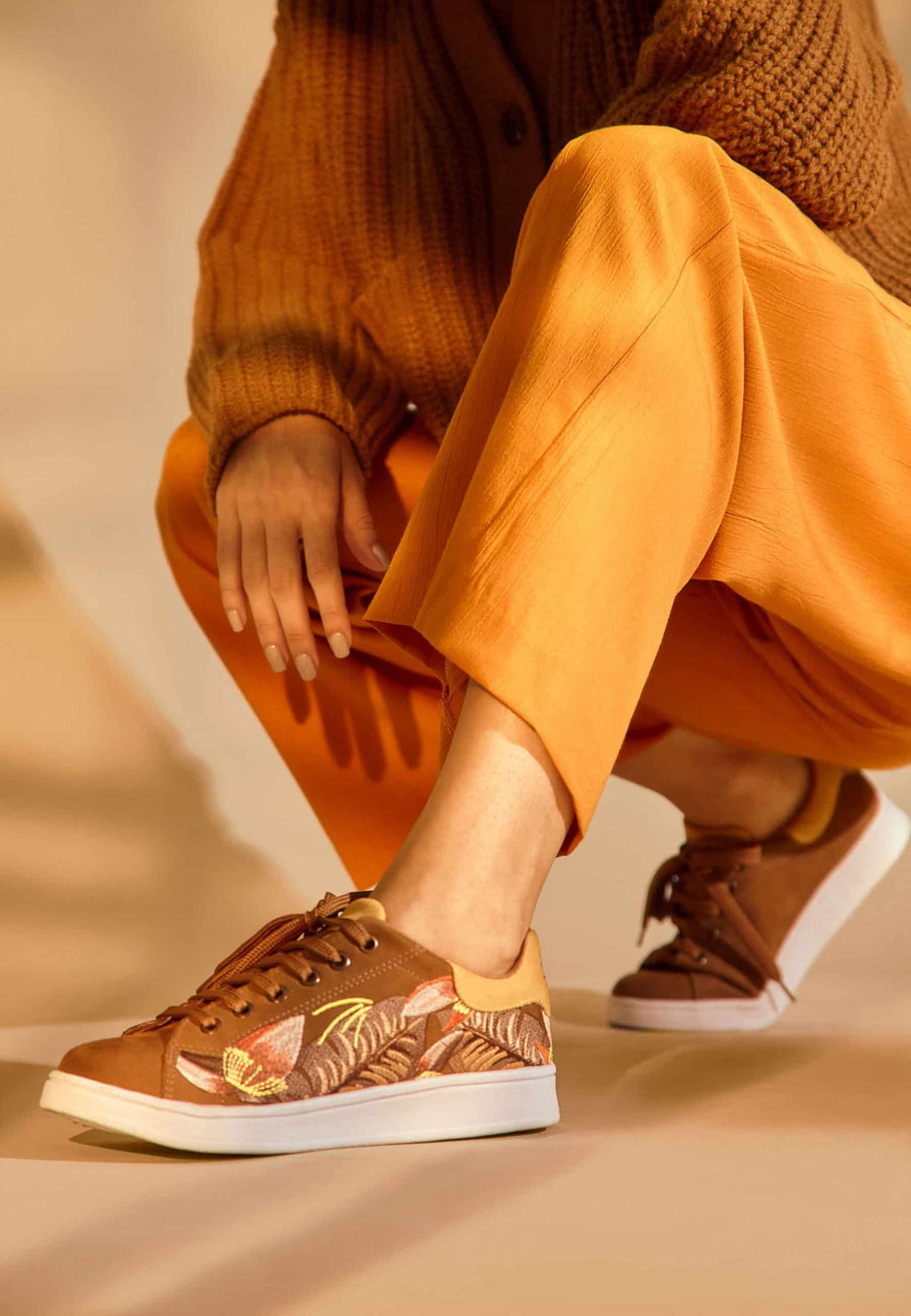 close-up detail of the intricate floral embroidery on soft brown suede mangara sneakers