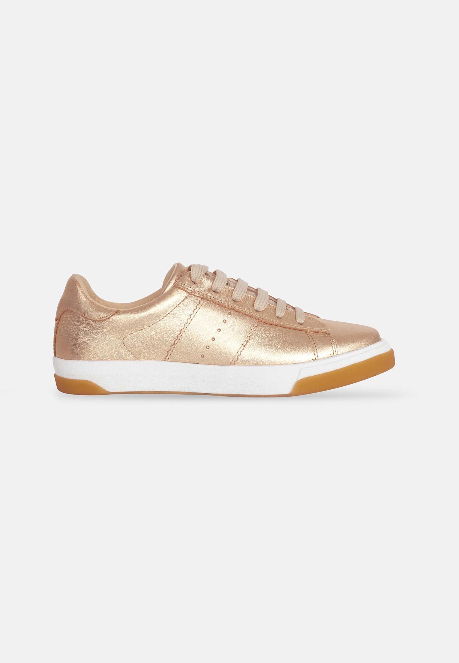 bold golden metallic leather sneakers for women on a dark urban background