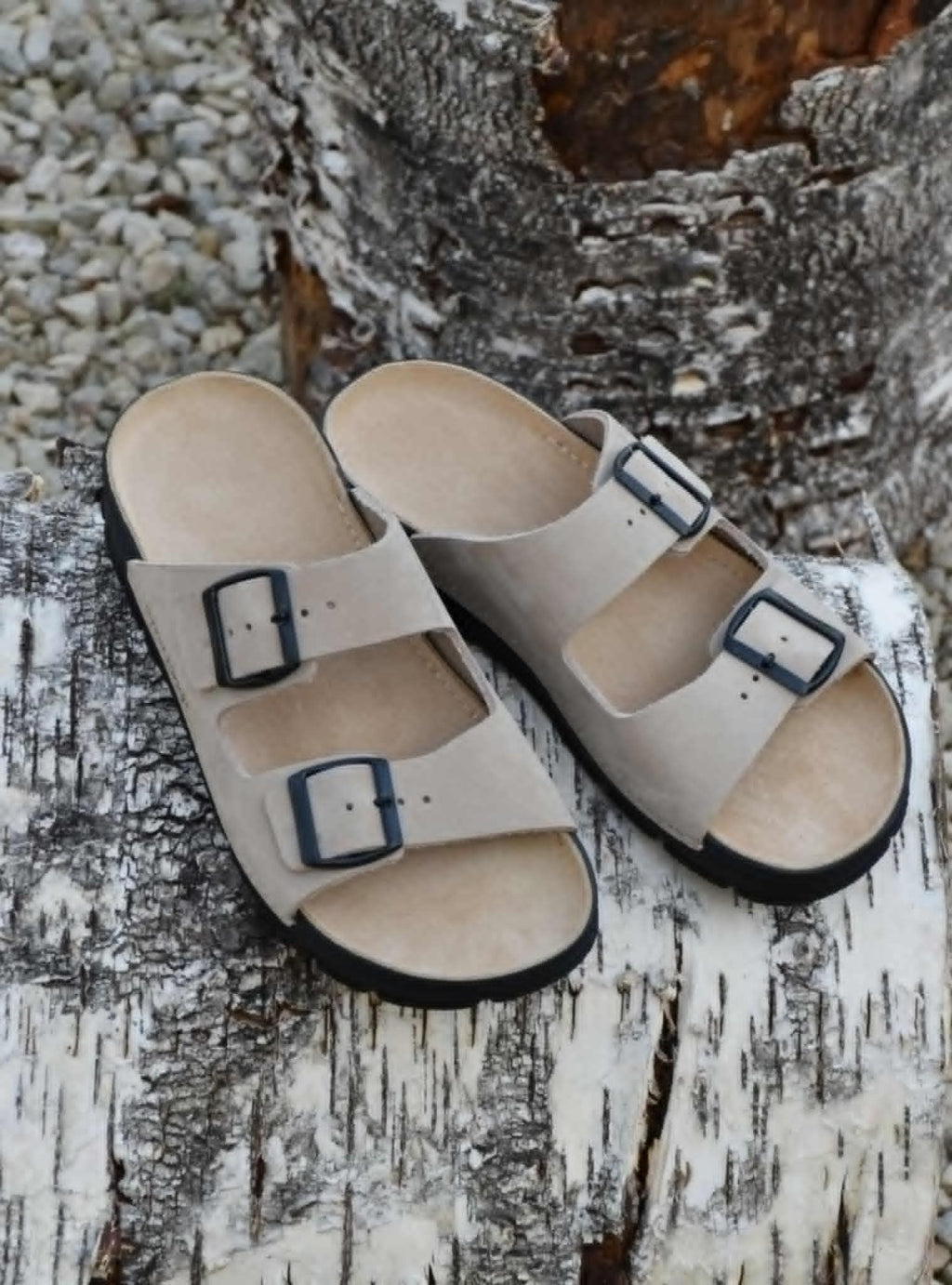 playful side view of beige leather sandals on a sunny patio, showing the adjustable buckles