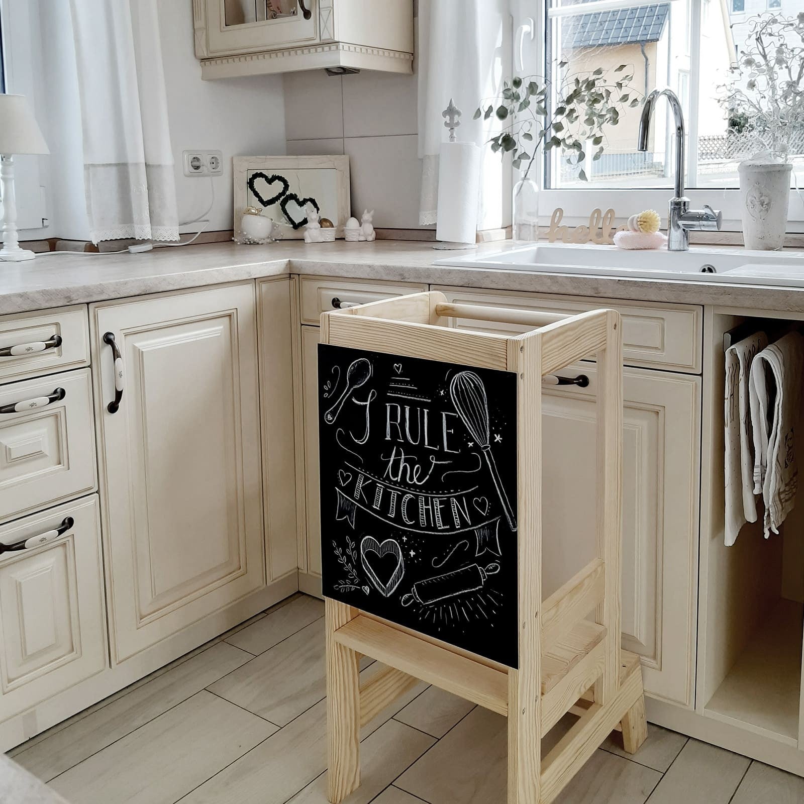 a child's joyful face peeking over the meowbaby wooden kitchen helper tower