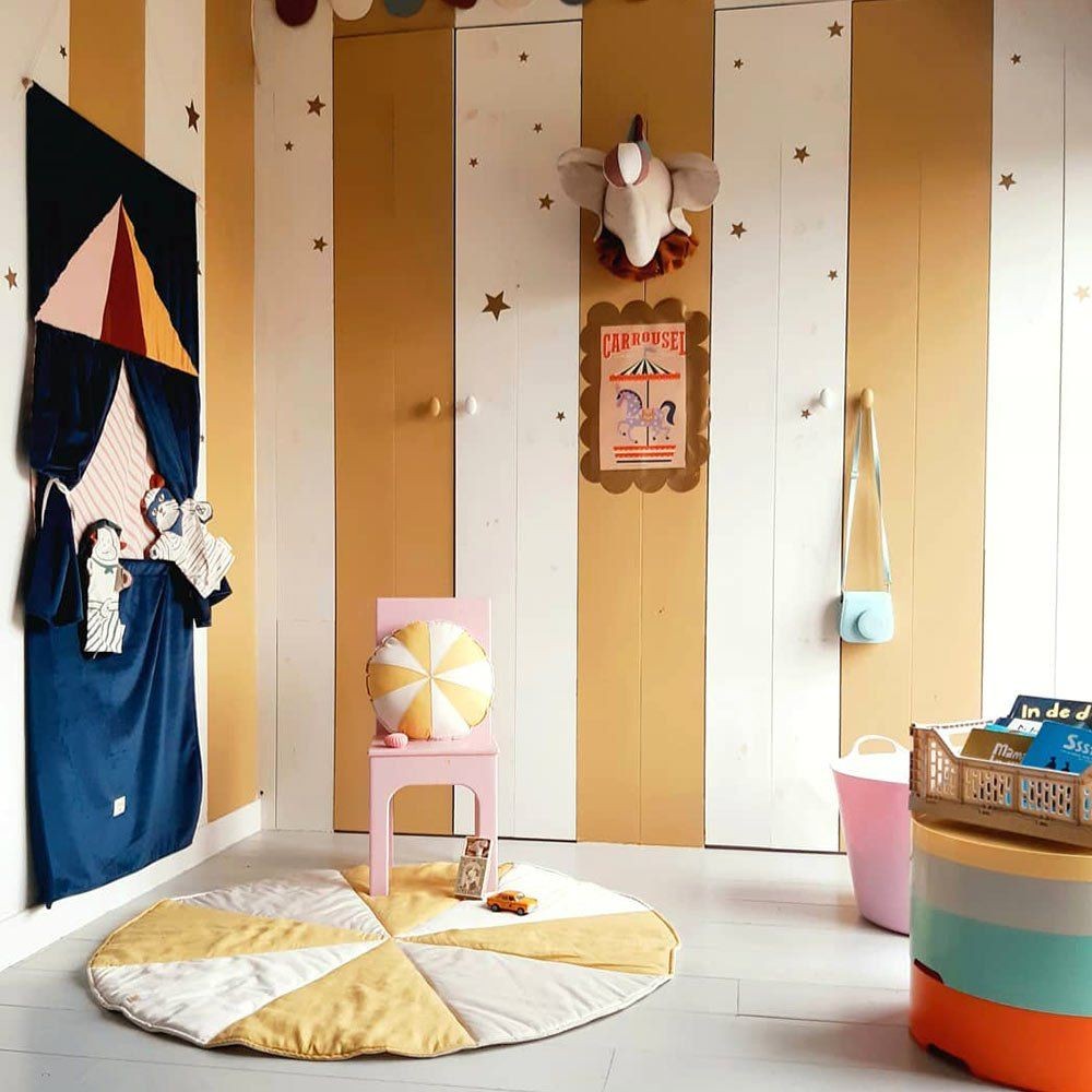 a child's hand playfully arranging shimmering gold star stickers on a bedroom wall