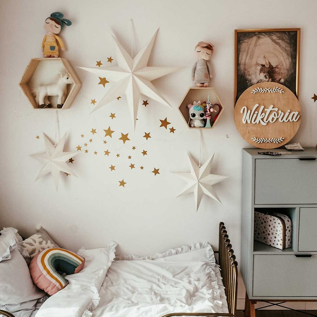 elegant gold foil star stickers arranged artfully on a nursery wall, casting soft light