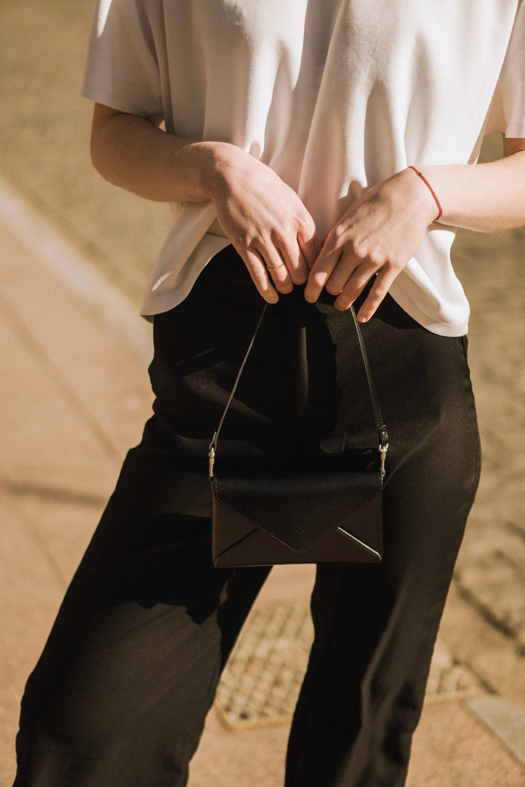 bold black mini clutch held confidently in hand against a dark dramatic background