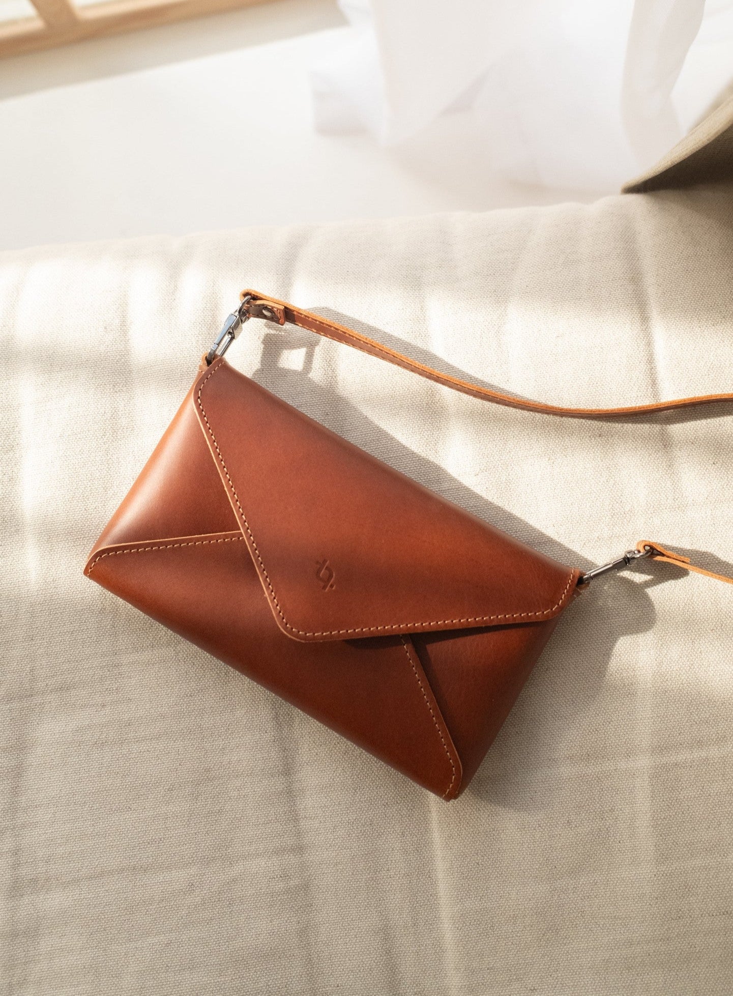 bold cognac leather mini clutch held confidently in hand against a dark urban backdrop