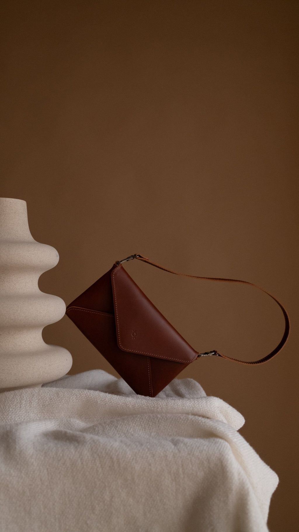 playful cognac leather mini clutch held in hand against a bright, fun background