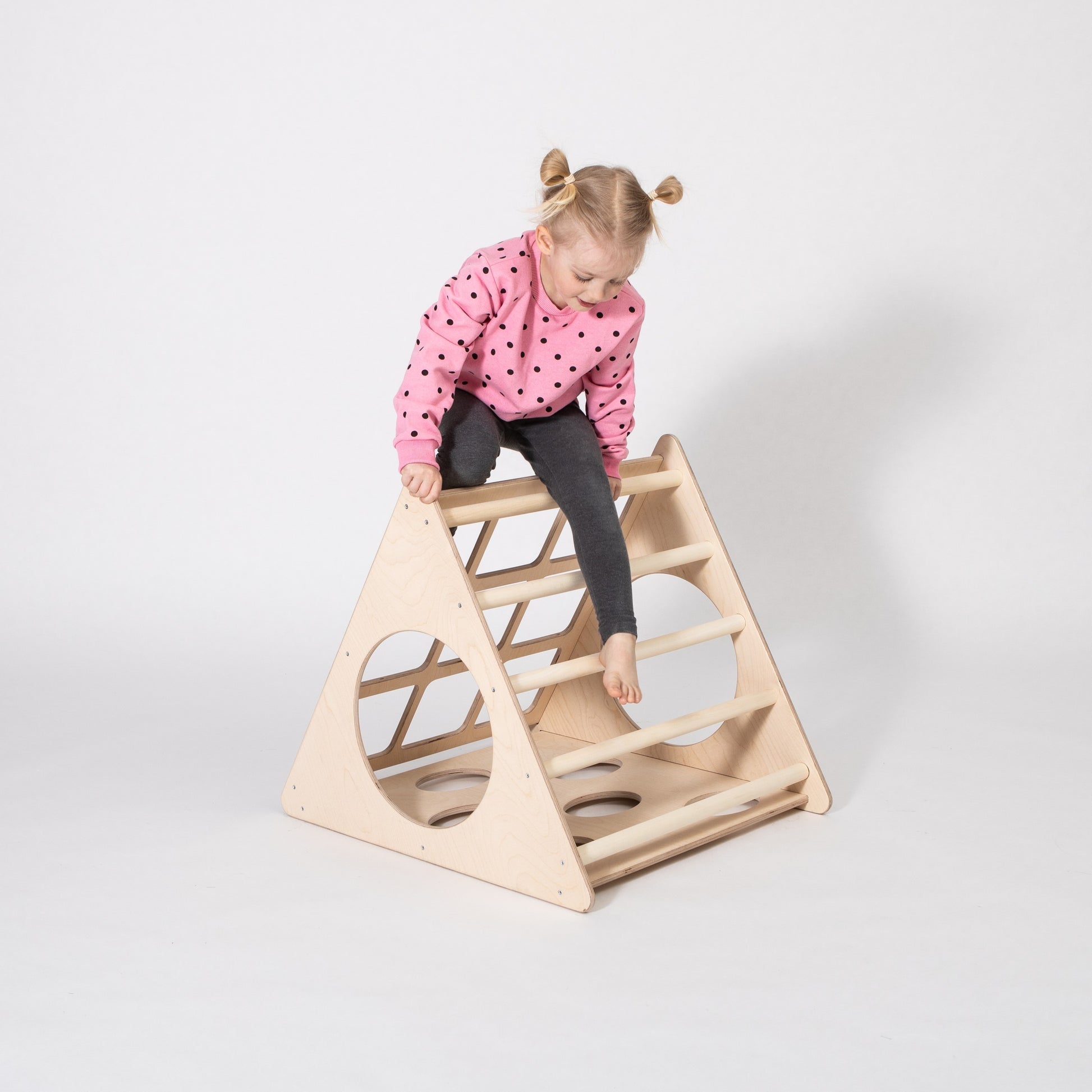 toddler laughing while climbing the birch plywood montessori climber from a playful low angle