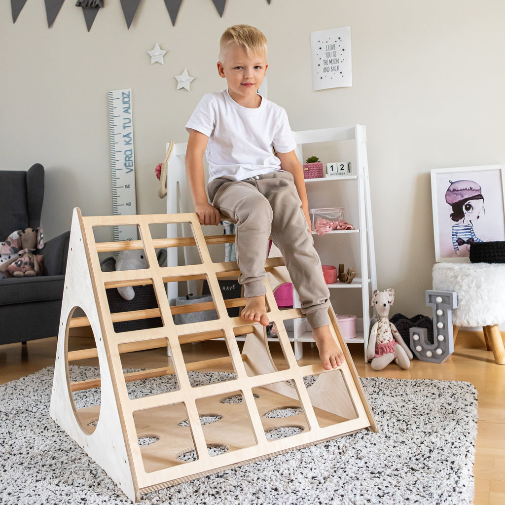 bold low-angle shot of a toddler conquering the montessori 3-angle climber