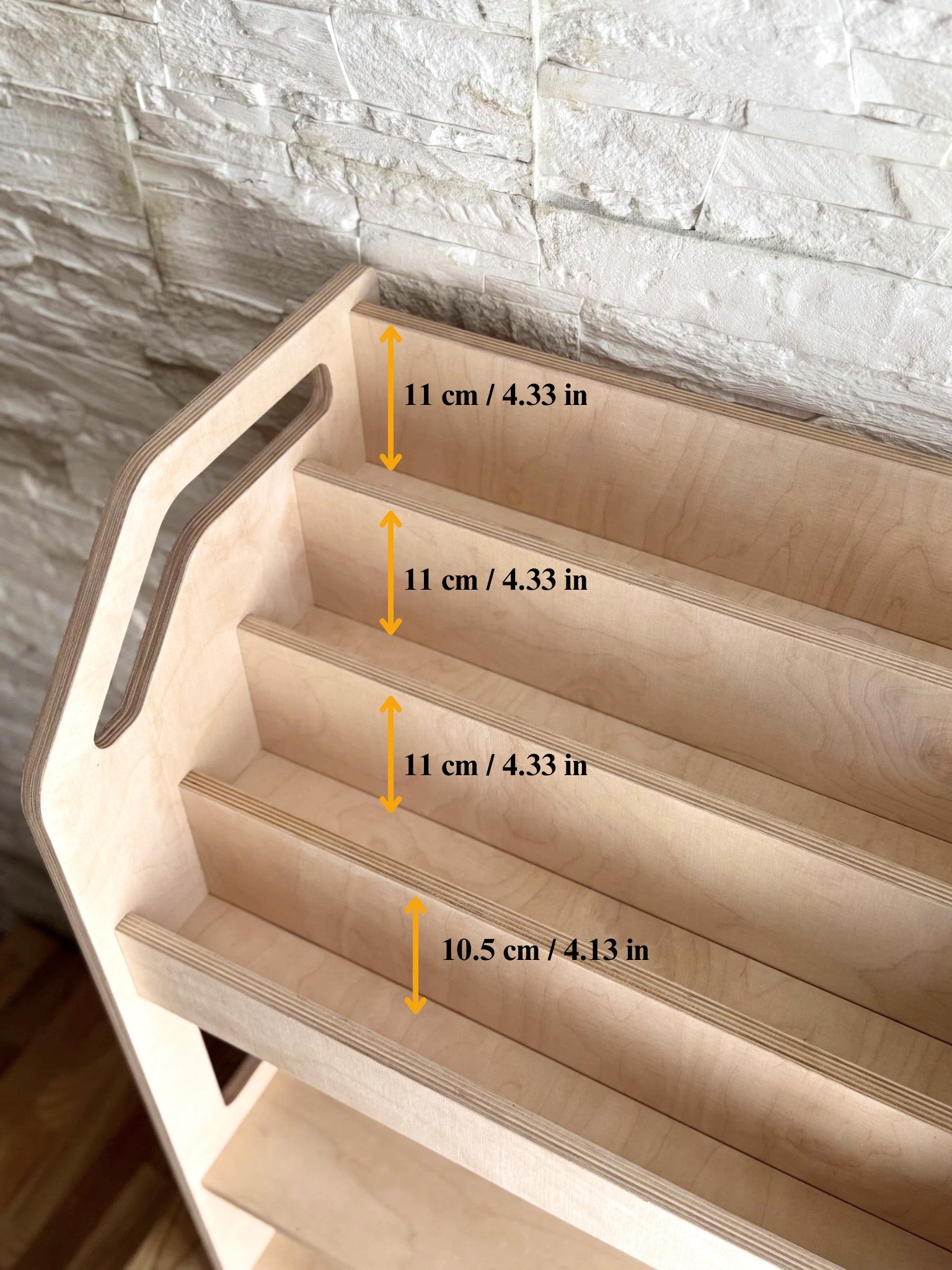 a soft-lit view of the birch bookshelf, showcasing its deep toy cubby and face-front shelves in a cozy nursery corner