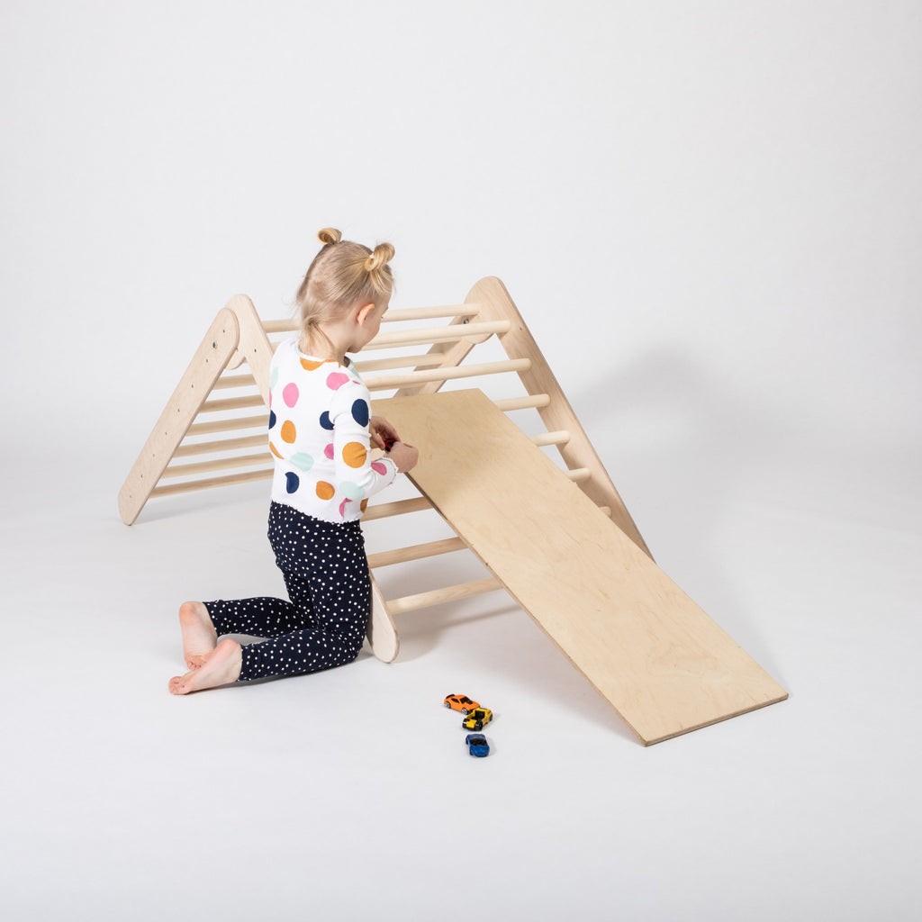 a bold low-angle shot of the montessori climbing triangle and ramp, showcasing its sturdy birch frame and adventure-ready design