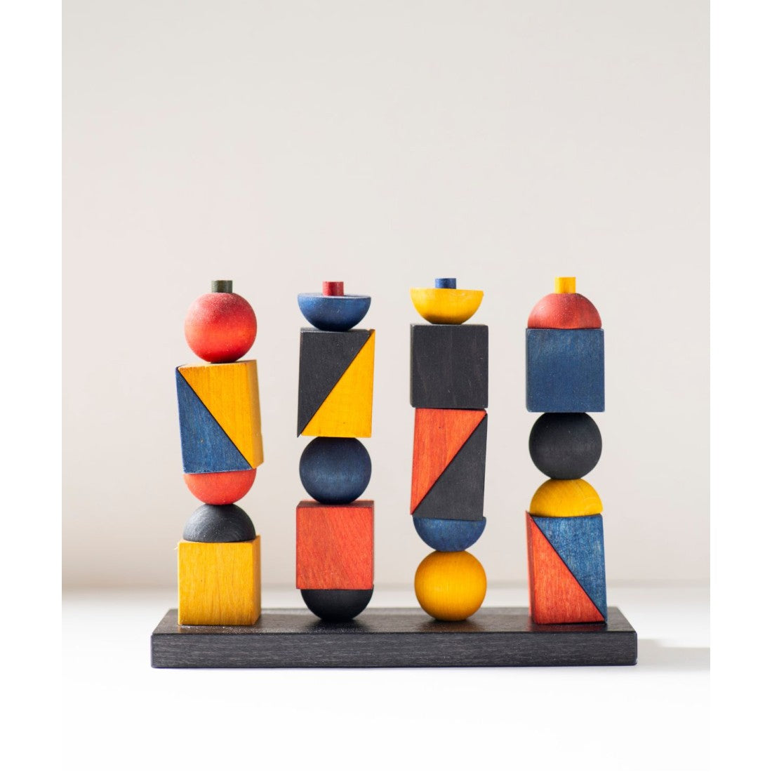 bold geometric wooden stacking toy in dramatic light showcasing its bauhaus-inspired design