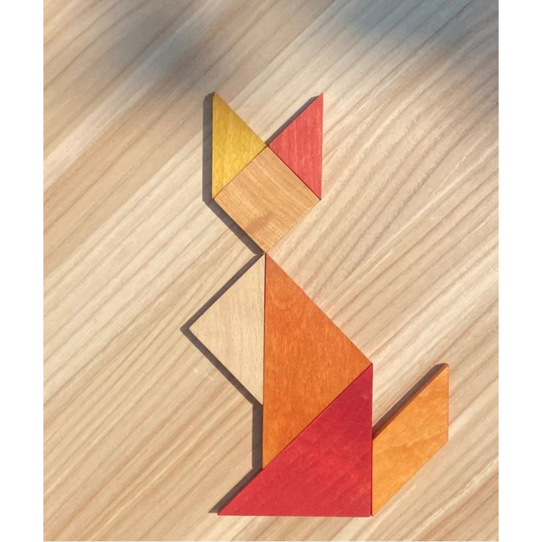 an elegant arrangement of the warm-toned wooden tangram puzzle on a minimalist leather surface