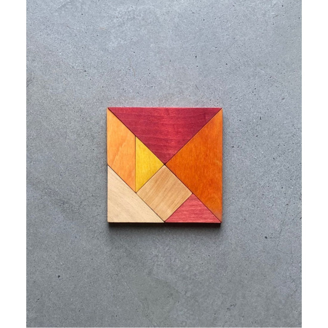 a bold overhead shot of the warm-toned wooden tangram pieces laid out in a dynamic geometric pattern